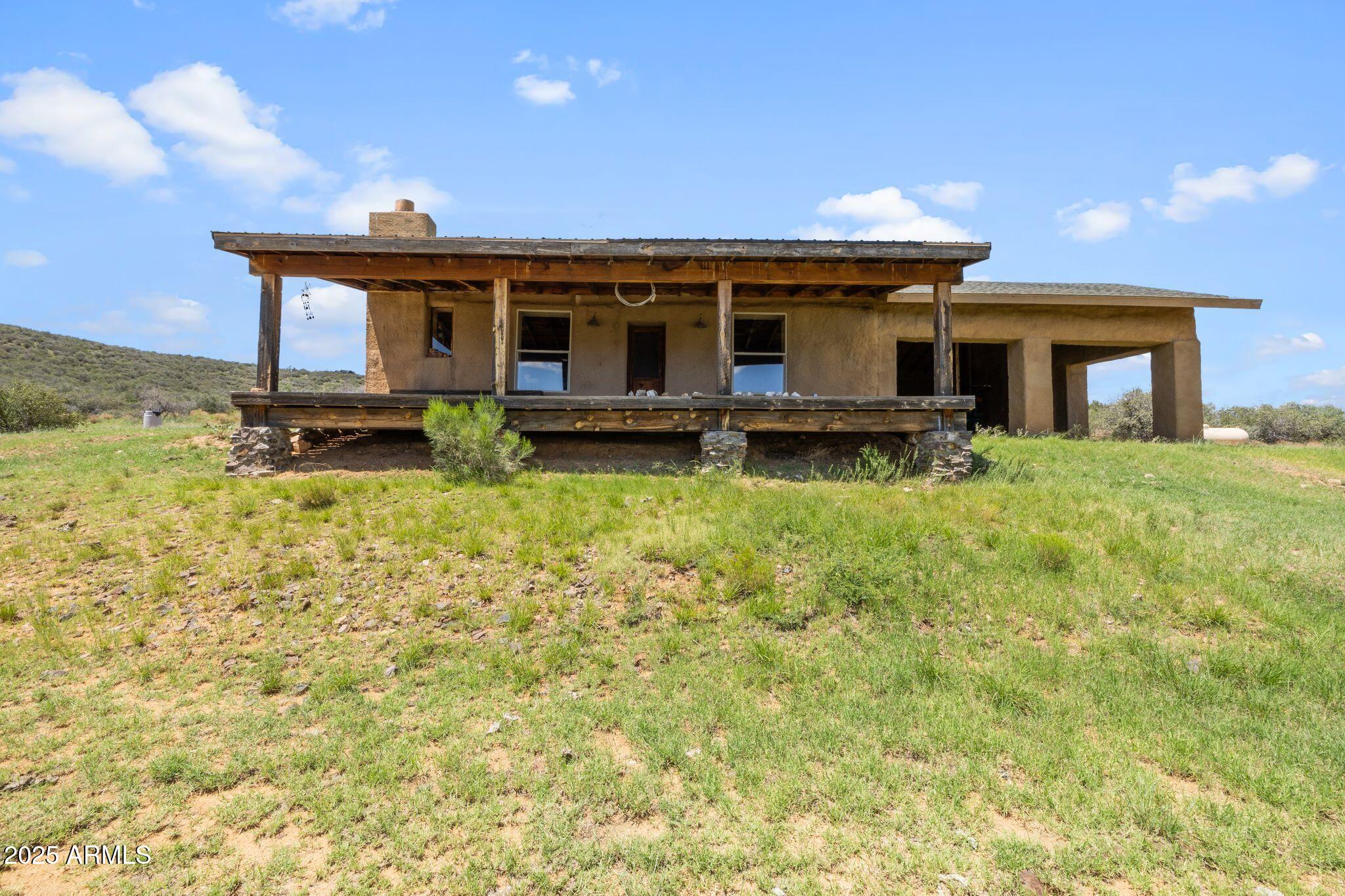 Discover sustainable living with panoramic views in every direction! Nestled on just under 20 acres of patented land, this 1,224 sqft straw bale home with 864 sqft garage offers an eco-conscious lifestyle with modern comfort and unique off-grid potential. Built with 48'' x 12'' x 16'' thick straw bale walls then covered with concrete, this home provides incredible insulation, keeping it cool in summer and warm in winter -- often needing no additional heating or cooling. When needed, enjoy a cozy wood burning fireplace and energy-efficient ceiling fans powered by a generator or install a solar system that is already wired for inverter and panels. Basic kitchen with propane stove gravity-fed hauled water, copper countertops. Additional features Pre-wired for solar - just add panels, inverter, and marine batteries or generator backup, Efficient tankless water heater, Compost toilet ( no septic installed ), Modern shower setup, and includes patented mining claim. This self-sufficient home is ideal for off-grid living or a retreat from the ordinary. The solar system will need to be installed for financing, but the infrastructure is ready  just plug and play. Whether you're a homesteader, minimalist, or investor, this rare property blends sustainability, privacy, and freedom in one of Arizona's most beautiful high desert landscapes.