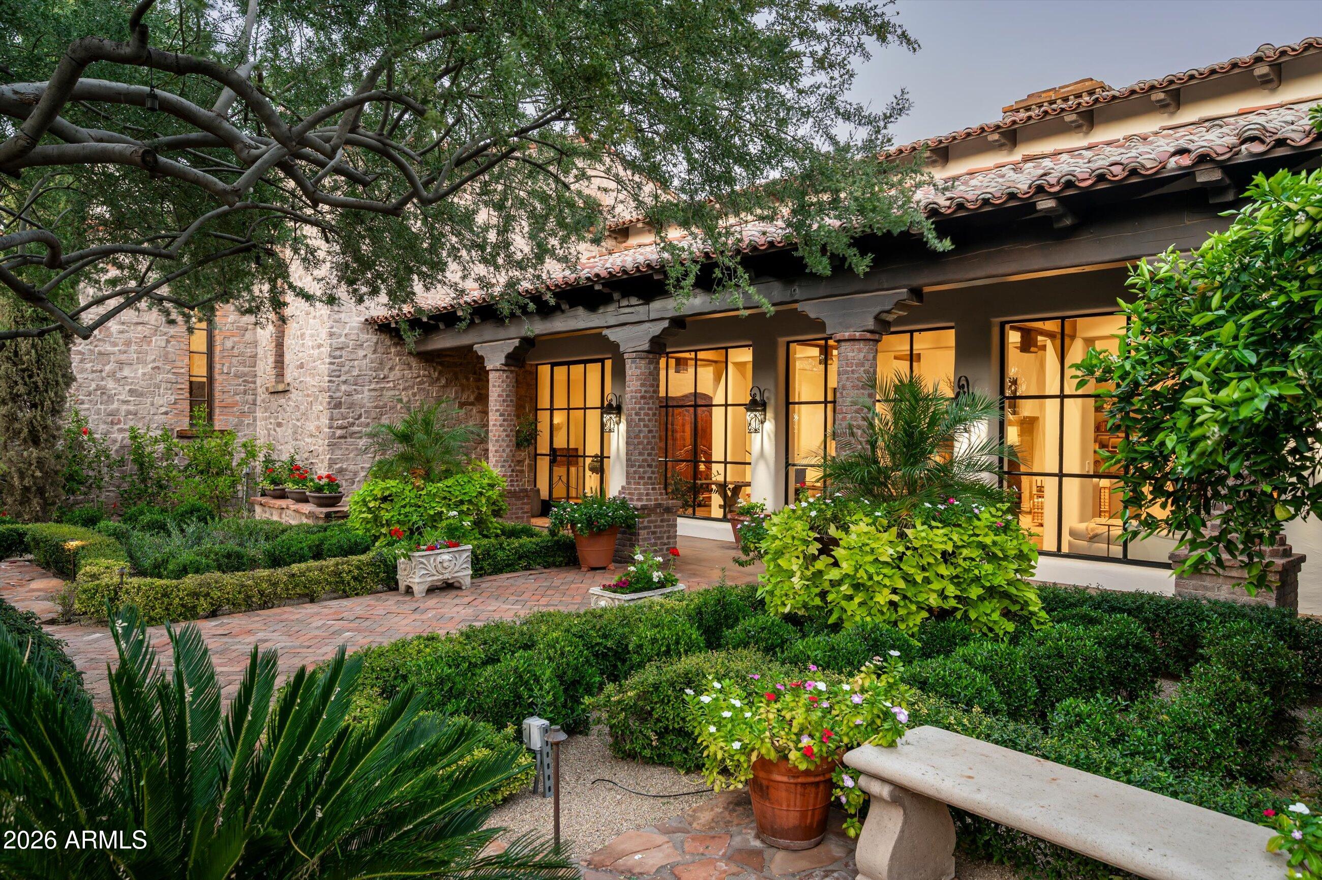 Fully remodeled and masterfully reimagined with interiors by the renowned firm Nate Berkus Associates, this more than 7,000-square-foot residence blends timeless European elegance, impeccable craftsmanship, and curated luxury. Set on expansive private grounds, the estate offers a rare opportunity to experience resort-style living in a home of extraordinary design and refined sophistication.

Soaring ceilings and walls of glass fill the home with natural light, highlighting its grand scale and refined architectural detailing.  Rich wood and limestone flooring create warmth and continuity throughout, while six hand-carved limestone fireplaces anchor the living spaces and reclaimed wood accents add depth and timeless character. The thoughtfully designed floor plan features four expansive en-suite bedrooms and four-and-a-half baths, each appointed with bespoke materials and elevated finishes. The private primary wing serves as a true sanctuary with two separate primary bathrooms, two generous custom closets, and a secluded courtyard with a private outdoor shower for a tranquil outdoor escape. 

At the heart of the home, the kitchen pairs beauty and performance. Custom cabinetry, slab marble surfaces, and a dramatic marble-and-bronze island form an architectural centerpiece, complemented by Sub-Zero refrigeration and a statement La Cornue range. A fully equipped secondary kitchen adds exceptional convenience for entertaining or daily living. 

The fully enclosed grounds evoke the feel of a private resort, with lush gardens, mature roses, vibrant blooms, and citrus trees, alongside a tranquil koi pond and wood-fired pizza oven. Multiple covered entertaining areas, artificial turf, and a dedicated greenhouse enhance both charm and versatility, while the infinity-edge pool, framed by limestone decking and a picturesque pergola, creates an idyllic setting for relaxation and entertaining. Two garages with space for 4.5 cars complete the offering. 

Located within walking distance of the iconic Arizona Biltmore, this exceptional estate offers a rare blend of privacy, scale, and resort-inspired living.