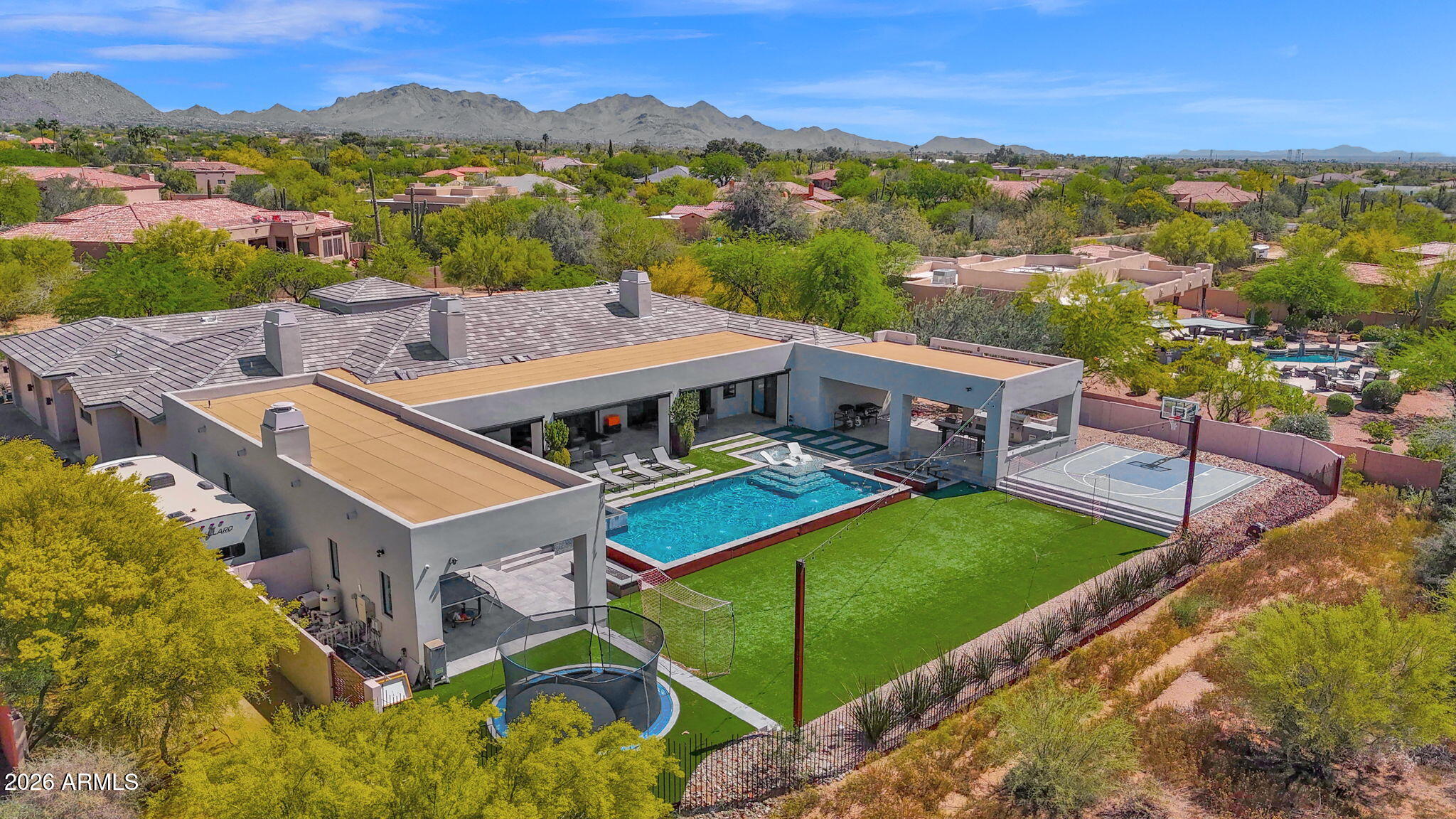 Absolutely stunning custom estate in North Scottsdale. Just shy of 6,000sq ft of living space and 10,000 sqft under roof, the property offers literally every amenity you can imagine.    The meticulous acre+ property is very private and boasts a resort style backyard and luxury finishes throughout.  The split & open floor plan offers 5 bedrooms 4.5 baths and large office with oak plank flooring throughout.  The guest house provides and additional bed and bath, with large living room and efficiency kitchen. 2 separate 3 car garages (One oversized) plus RV parking. The impressive great room features a beautiful gas fireplace with tile detailing and custom glass pocket doors designed for seamless indoor/outdoor living.  The chef's kitchen is equipped with an enormous island, beautiful (more) custom cabinetry, and professional appliances (wolf, subzero etc.) The primary suite boasts a gas fireplace, private patio exit with multi slide doors, and spa style bathroom with designer tile finishes, dual vanities, large walk-in shower, separate soaking tub and two walk in closets. Down the primary hall is a gorgeous powder bath, expansive laundry room, storage room, and entry to the large garage. The south wing of the home features three bedrooms with two suites each with uniquely designed bathrooms.  The backyard resort sanctuary includes a heated pool and spa w/ relaxing water features, turf yard, sport court and trampoline. The large covered patio includes an outdoor kitchen with built-in Wolf BBQ, several gas fireplaces & commercial heating system making this the perfect space to enjoy year round. 
Additional upgrades and features include premium windows & sliding doors, pavered driveway, multiple mechanical sun shades, Carrier multi-zoned AC/heat pump system and multiple smart home features. Carefully constructed and built new in 2018 by the Owner/General Contractor.  This smaller North Scottsdale neighborhood provides a serene & private setting yet is only minutes from all that Scottsdale has to offer. This home is loaded and an absolute must see.