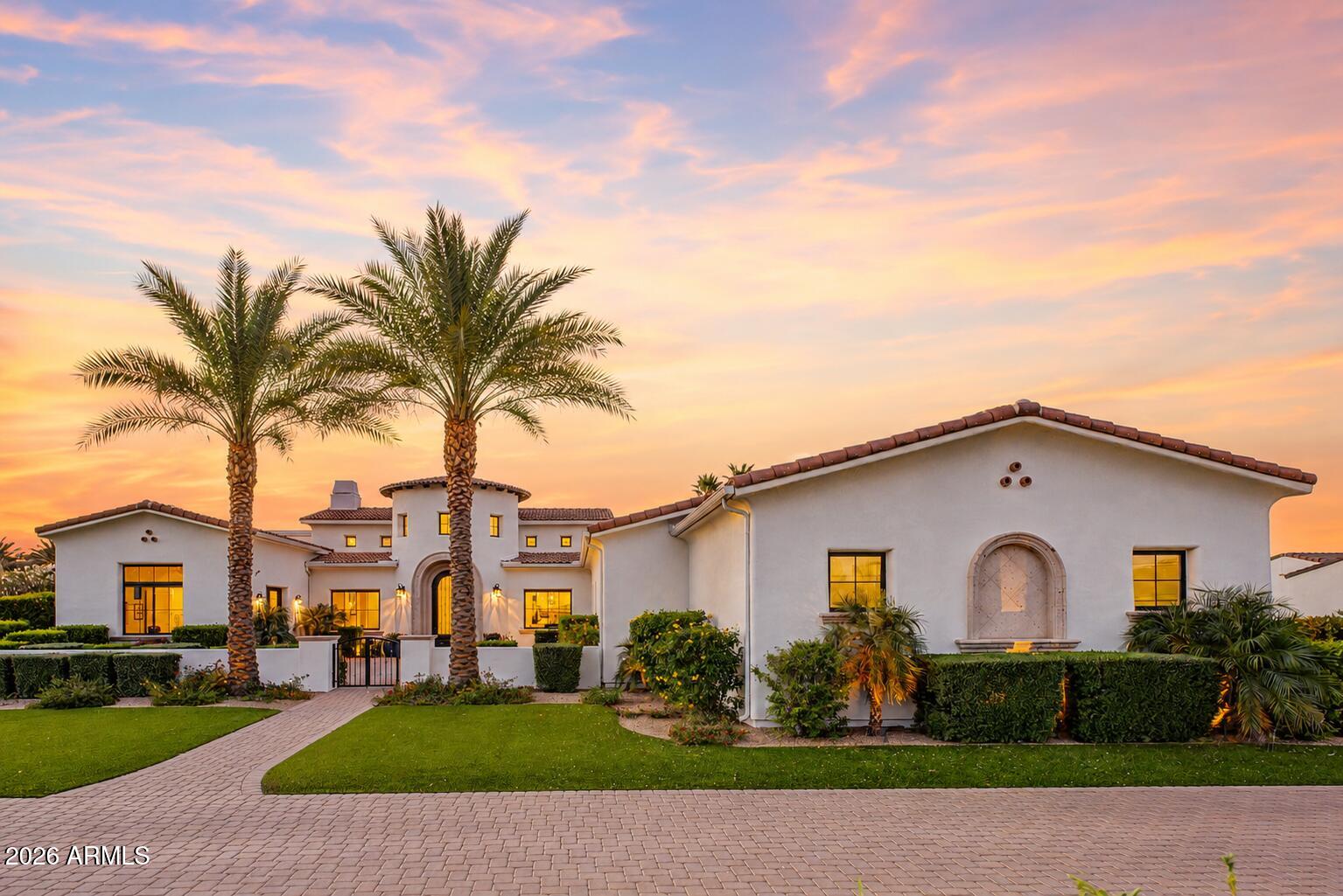 This Paradise Valley Gated Custom Estate built in 2020 by award-winning builder Gray Properties, Inc. is set on a desirable north/south acre-plus lot and offers a 4-car extended-height and-length garage.
The home features indoor-outdoor living with a detached guest house, heated pool and spa, ramada, sport court/pickleball court, putting green, batting cage, built-in BBQ with sink and bar, and an expansive view deck. The main residence includes automated sliding pocket doors, high ceilings, real rough-sawn wood beam ceilings, Vintage French Oak wood flooring, and a chef's kitchen with Sub-Zero and Wolf appliances. The detached guest house includes its own kitchen, bedroom, bathroom, and laundry, creating an ideal setup for guests, extended family, or private living quarters. The view deck captures dramatic camelback and mummy mountain views and includes a flexible space for workouts, massages, yoga, or study, with a sliding glass wall. Located near Old Town Scottsdale, fine dining, Fashion Square, Ritz-Carlton, resorts, spas, golf, hiking, biking trails, and excellent Paradise Valley schools, this home delivers luxury living in one of Arizona's most sought-after locations.