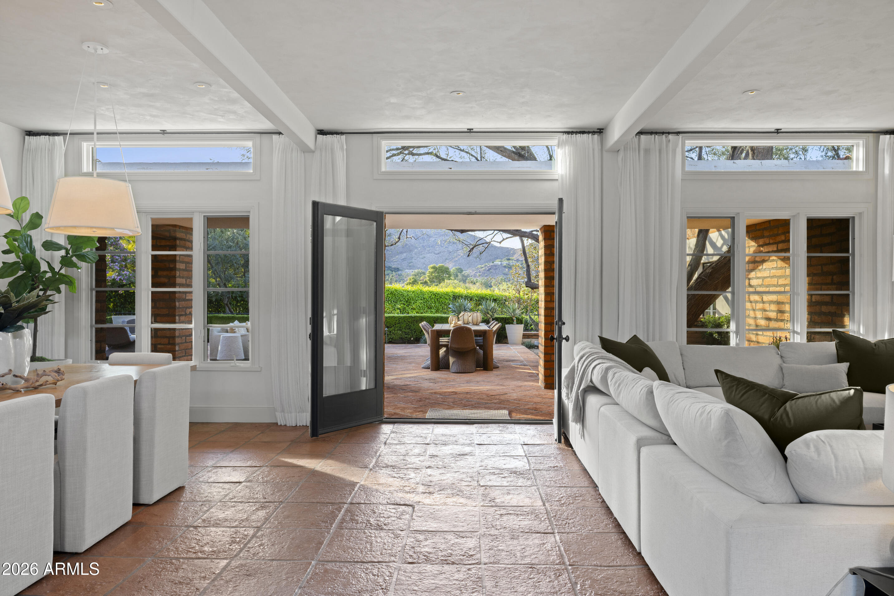 A rare offering on the 4th fairway of Paradise Valley Country Club, this 6604 sf desert/modern - extensively remodeled (GM Hunt 2013) estate blends timeless character with a refined modern edge. Highlighting a private courtyard pool, the home features Saltillo and wood floors, floating beam ceilings, and restored antique doors. Framed by views of Mummy Mountain in the front and the Phx Mountain Preserve beyond, the home sits along the golf course, offering a picturesque setting. The backyard is designed for both entertaining and everyday living, w/multiple patio spaces, expansive lawn, mature trees, and a curated vegetable garden. The primary suite features vaulted ceilings, a spacious bathroom, 2 water closets and large dressing room. The reimagined kitchen showcases mid-century modern... influence with Viking appliances, double ovens, a prep kitchen, and ample storage. Multiple living areas open seamlessly to lush grounds with olive and citrus trees, grass, and a brick patio w/ firepit. Three additional bedrooms, an office/library, 4 car garages + flexible spaces offer versatility. A warm, architecturally rich property in one of Paradise Valley's most coveted locations.