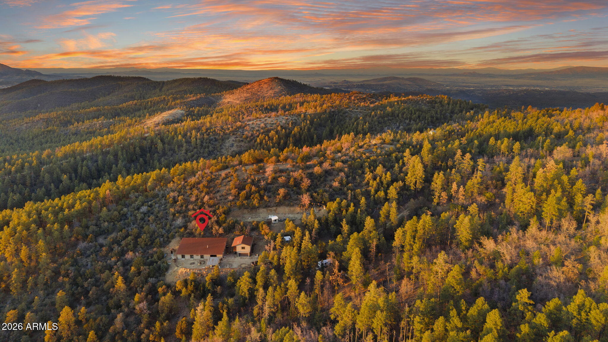 Private mountain compound on 4+ acres with sweeping views across Prescott's pine forest. The main home offers expansive open living areas with raised ceilings, abundant natural light, & flexible living space. Built with energy efficiency & sustainability at its core, the property includes a rainwater collection system & hillside design, providing natural insulation and year-round thermal stability. The spacious main level offers a seamless kitchen & living area, along with generously sized bedrooms featuring walk-in closets. The upstairs flex space adds versatility for office, media, or additional living. A detached 800 sqft guest house provides separation for extended living or guests. A hillside sauna defines the mountain retreat setting, with acreage suited for equestrian facilities.