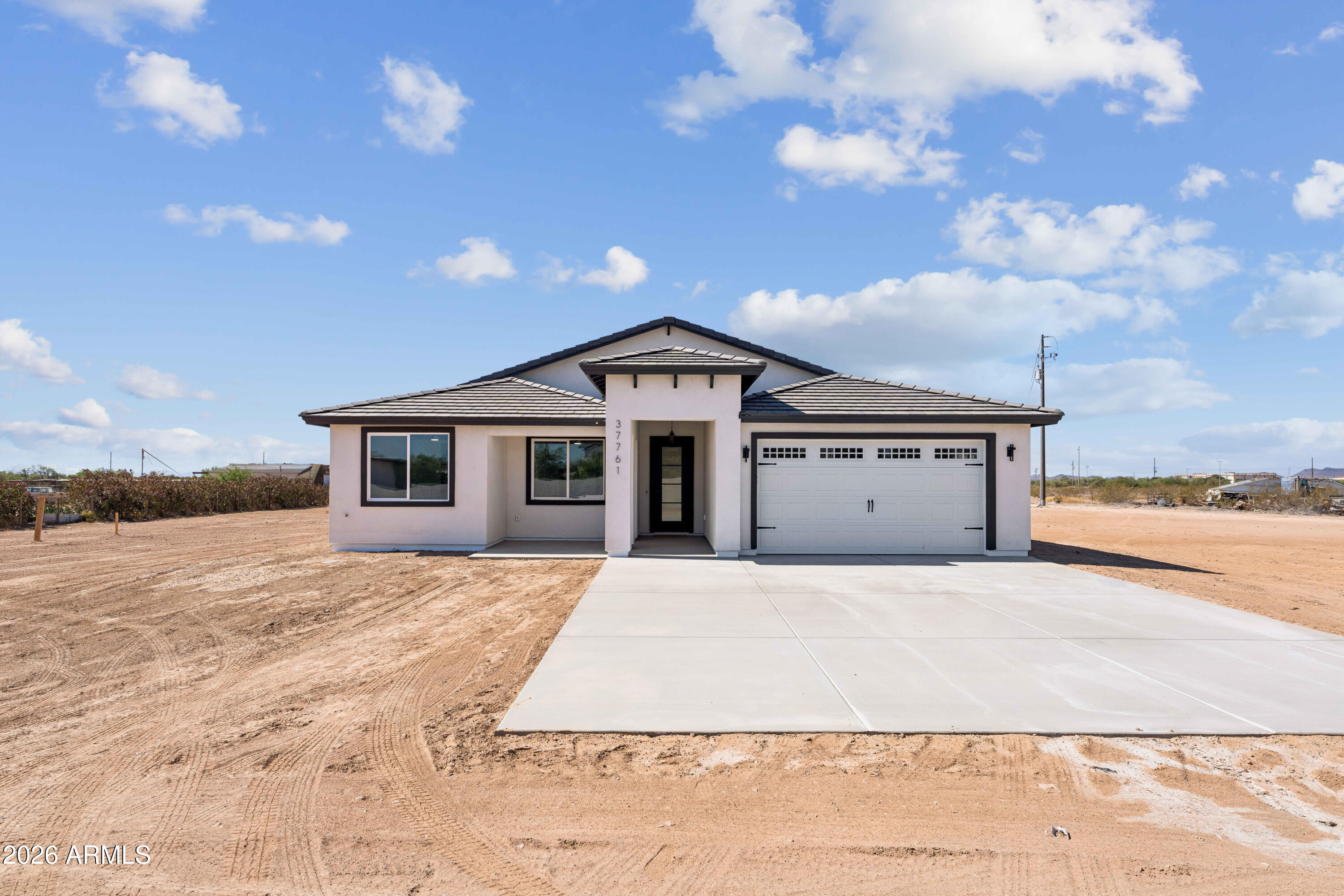 Experience custom desert living in this beautifully designed 4-bedroom, 3.5-bath home in Tonopah featuring modern architecture, soaring ceilings, oversized doors, and an open-concept layout filled with natural light. Offering approximately 3,224 SQFT under roof (2,297 livable), this new build showcases Alpino White 20x40 porcelain tile flooring, clean modern finishes, and an airy, expansive feel throughout.
The spacious kitchen features custom-style cabinetry, a large island, and appliances backed by a 2-year warranty. A split floor plan provides privacy and comfort, while the primary suite offers a beautifully designed bathroom and generous walk-in closet.
Situated on a spacious lot with room for RVs, toys, animals, or future additions, this property combines modern living with flexibility and open desert surroundings. Shared well servicing only 2 homes adds efficiency and long-term value. A second similar home is also available next door, creating a rare opportunity for multi-generational living, investment, or extended family ownership.