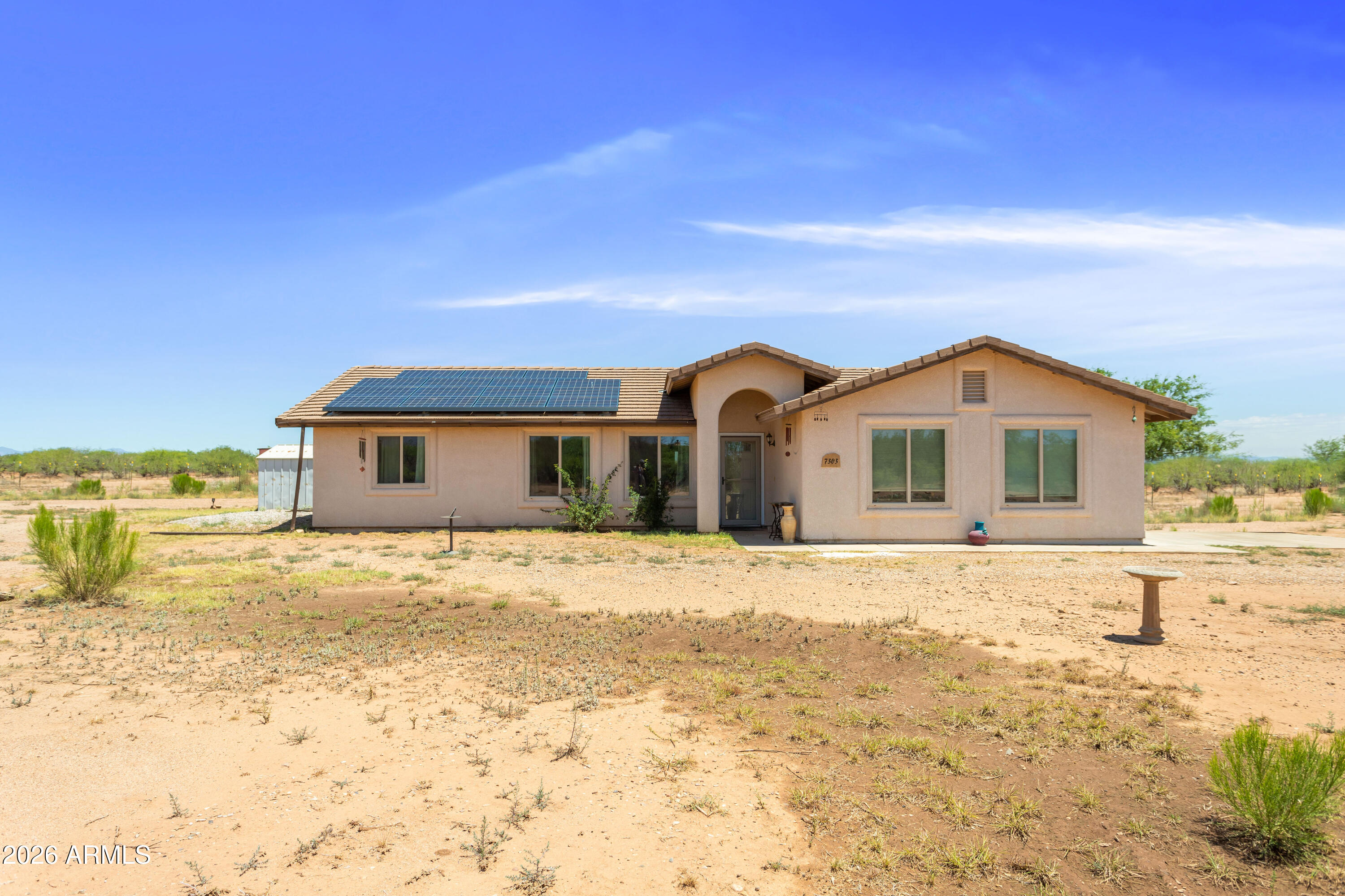 Enjoy wide-open desert views from this inviting horse property with room to spread out! This home features paid-in-full Tesla solar, new flooring, fresh interior paint, and new appliances, including a gas stove. Relax year-round in the Arizona room with an above-ground jacuzzi or take advantage of the fenced areas ideal for animals, hobbies, or extra space. A shed and Conex storage container on the property provides great additional storage for tools, feed, tack, or equipment. A wonderful opportunity to enjoy peaceful Arizona living with practical upgrades already in place.