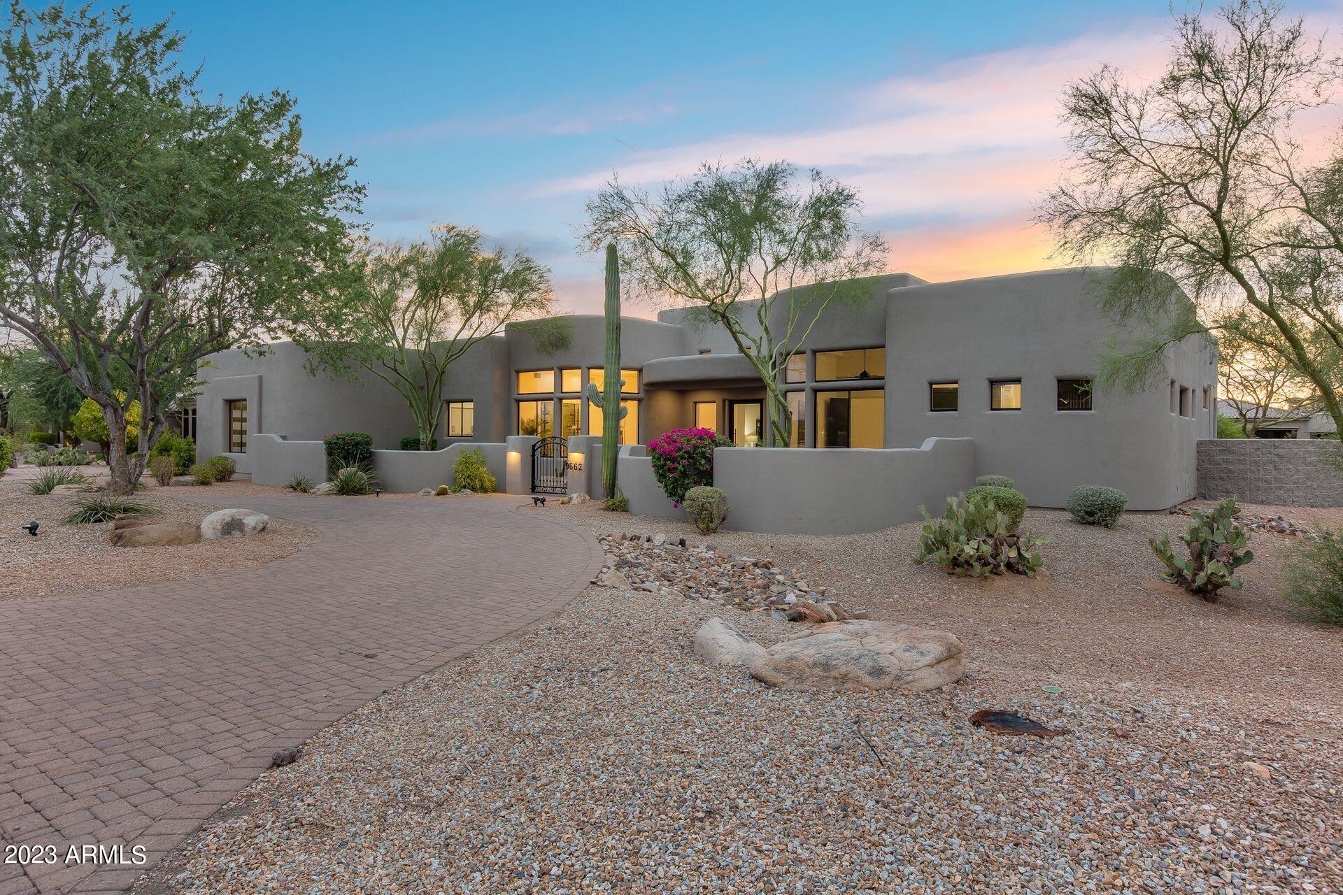 The warmth of this contemporary southwestern home is apparent from the moment you walk through the front door. Situated on a ¾ acre lot, with the arroyo running behind the home, you will truly feel as though you have found the perfect desert oasis. The mixture of textures - wood floors, stack stone brick fireplaces, wood cabinets, smooth coat walls, plush carpet and unique tile all come together to create a spectacular luxury home just waiting for you, your friends, and your family to enjoy. Creative architectural features and amenities are thoughtfully used throughout the home. The dining room ceiling feature enhances the area complete with a custom refrigerated wine display and is within steps of the amazing kitchen. Complete with a walk-in pantry, Monogram fridge, 48'' Monogram gas range, Monogram dishwasher, Monogram microwave drawer, pot filler, open shelving, and custom vent hood - it has it all. You'll never run out of counter space or cabinets, and with it opening to the charming family room (with a fireplace, of course!), this living area will be the place to gather for friends and family.  The primary bedroom boasts a fireplace with stack stone brick surround and a bathroom with steam shower and has its own access to the backyard. Nothing was missed, from the metal pivot doors to the finished garage floor, you will see that the remodel was complete and high quality. The backyard has turf, a sparkling pool with water feature, heated spa, outdoor fireplace, covered patio, and built-in BBQ making it the ideal place to be regardless of the time of year. Years of stunning sunsets and starry nights will be yours to enjoy with this beautiful home.