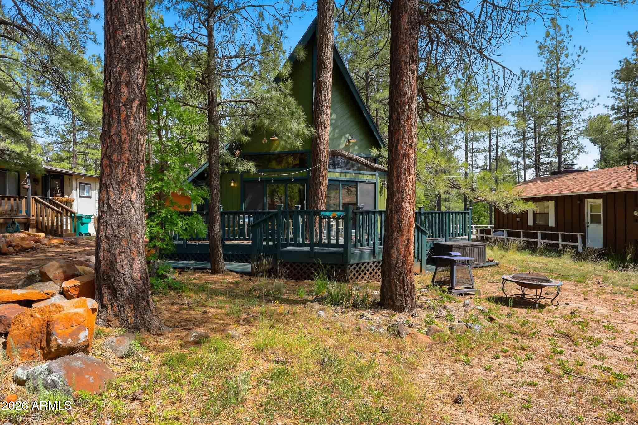 Experience the charm of Munds Park in this highly sought-after A-Frame cabin! Recently updated and move-in ready, this mountain retreat features brand-new cabinets, granite countertops, fresh interior paint, newly painted decking, new flooring, a new roof, newer HVAC, and newer heater. The warm and inviting interior showcases vaulted ceilings, a dramatic fireplace, and an open staircase. Downstairs offers a spacious great room, two bedrooms, and a full bath. Upstairs includes a versatile loft, additional bedroom, and full bath. Ample front and side parking. Enjoy cool summer evenings on the expansive front deck -- the perfect place to relax and entertain in beautiful Munds Park!