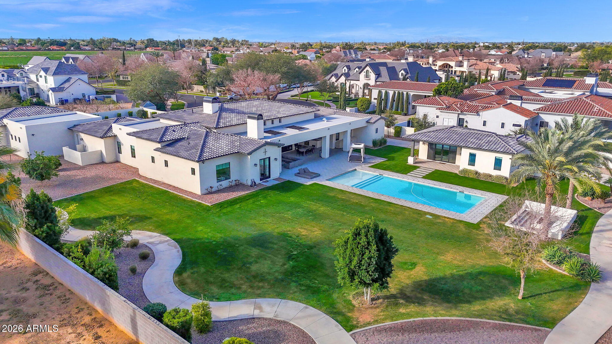 Welcome to an extraordinary custom estate in Mesa. Set on over one acre cul-de-sac lot in the coveted Legacy enclave. Designed for luxury living, grand entertaining, and high-performance fun, this one of a kind property delivers an unmatched lifestyle experience. Step inside to the family room with soaring 14 foot ceilings accented with dramatic all wood beams and an inviting gas fireplace. Massive 30 foot sliding glass doors seamlessly connect indoor and outdoor living. The wide open family room flows into a spectacular double island eat-in kitchen with breakfast bar, quartz countertops,  double sinks & double dishwashers, reverse osmosis system, 6 burner Wolf cooktop with grill, Wolf double ovens, Sub-Zero refrigerator, beverage fridge with wine cooler, ice machine, butler's pantry, hidden 9' x 5' walk in pantry, dedicated coffee bar. This kitchen was built for serious culinary performance and seamless entertaining. The thoughtfully designed split floor plan offers privacy and comfort for all. Primary Suite Retreat has: Gas fireplace, private patio access, 11 foot ceilings, dual closets with stackable washer/dryer, space to add a private steam room, spa like bath with walk in shower, soaking tub, and urinal. There are an additional three en suite bedrooms. All with walk in closets. All three with walk in showers and one with an additional soaking tub. Additional interior highlights include: Private office. Dedicated theater room with Savant stereo system and berber carpet. Oversized laundry room with island, hanging space, and attached 9' x 9' storage room. Powder room bathroom for guests. The home features: White oak engineered hardwood flooring. 8 inch baseboards. Custom tongue and groove cabinetry with soft close throughout. Abundant storage at every turn. Detached Casita is perfect for guests or multi generational living, the private casita includes: Bedroom, bathroom with walk in shower, living space, wet bar with fridge and microwave. The resort style backyard is an entertainer's dream: Sparkling heated 50' x 20' pool with expansive child's play shelf. Theatre style seated fire pit. Huge covered patio with built in misting system. Outdoor Coyote gas BBQ. Dual outdoor TVs. Four zone built in surround sound with directional exterior speakers. Whether hosting gatherings or enjoying a quiet evening under the Arizona sky, this space was designed to impress. The expertly landscaped grounds blend artificial turf and natural grass, highlighted by mature citrus trees including orange, lemon, and tangelo. A large grassy play area provides even more room to enjoy the outdoors. Car enthusiasts and hobbyists will be in awe of the 7 car garage, including one bay with pull through access to the backyard. Outfitted with built in storage, a dedicated workspace. It's as functional as it is impressive. Elegant driveway pavers set the tone upon arrival, while double RV gates open to reveal a truly unique feature. A private go kart race track that encircles the entire property, complete with straightaways, sweeping 90-degree turns, and thrilling hairpin curves. This Legacy masterpiece combines craftsmanship, innovation, recreation, and resort level amenities. All on a rare, expansive lot in Mesa. A truly exceptional property designed for those who expect more. Main house is 5448 sq ft. Casita is 700 sq ft. Total sq ft 6148.