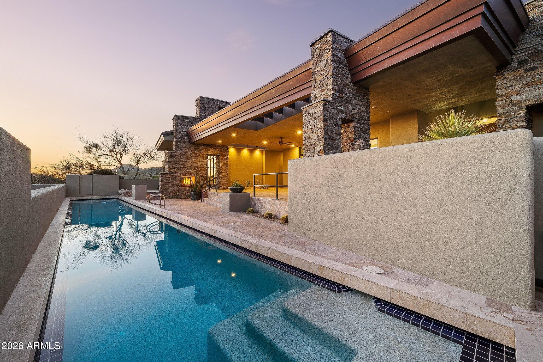 Framed by sweeping views of Pinnacle Peak and city lights, this fully reimagined residence is set within the prestigious guard-gated community of Desert Mountain, offering privacy and refined desert living.

Expansive walls of sliding glass create seamless indoor-outdoor flow, opening to a generous covered patio complete with a built-in BBQ, fireplace, lap pool, and spa--perfectly suited for both vibrant entertaining and quiet evenings beneath the Arizona sky.

The thoughtfully designed main level includes three en-suite bedrooms and a dedicated office, complemented by a detached guest casita that provides comfort and flexibility for visitors. The chef's kitchen is appointed with Sub-Zero and Wolf appliances, custom cabinetry, and elevated finishes throughout. The primary suite serves as a private retreat, featuring a spa-inspired bath, generous walk-in closet, fireplace sitting area, and direct access to the patio and spa. 

The three-car garage offers ample parking and storage, with convenient access to the main living level via steps or elevator.

Located within one of North Scottsdale's most exclusive private golf communities, this home embodies the Desert Mountain lifestyle.