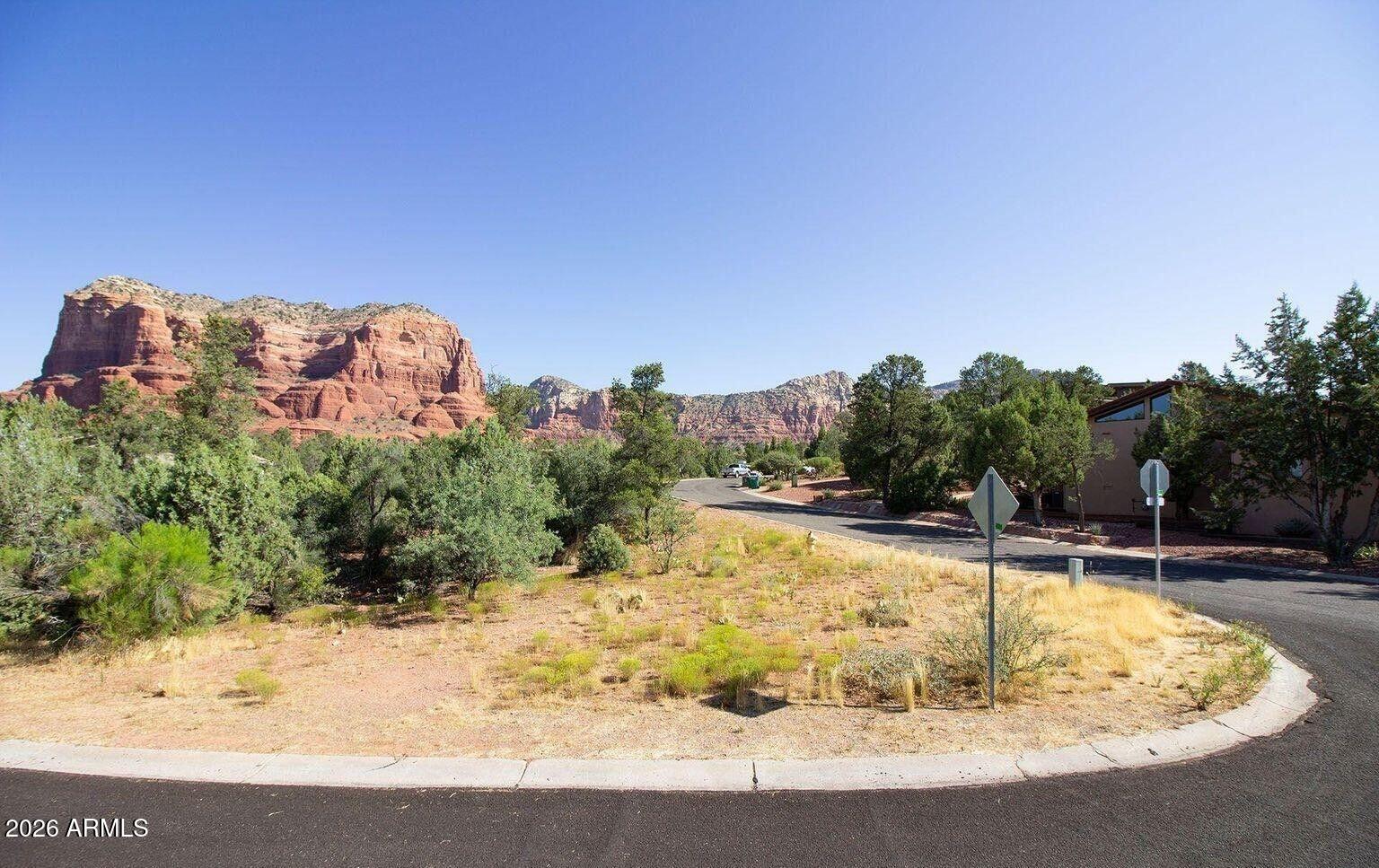 Gorgeous parcel in Piñon Woods, one of the VOC's most desirable and upscale subdivisions. This rare offering features a county-approved 2,716 sq. ft. level building envelope thoughtfully positioned within a scenic, natural arroyo—creating exceptional privacy and a serene sense of retreat. The lot offers spectacular, unobstructed views of both Bell Rock and Courthouse Rock, positioned to capture Sedona's renowned light and sunsets. All utilities are in place, including underground natural gas, sewer, APS electric, & water. Detailed architectural plans for a luxury residence are completed and approved by the HOA and are included, providing a significant head start and reducing time, cost, and permitting uncertainty. Minimum home size is 1,600 sq. ft. with a 30-day minimum rental requirement