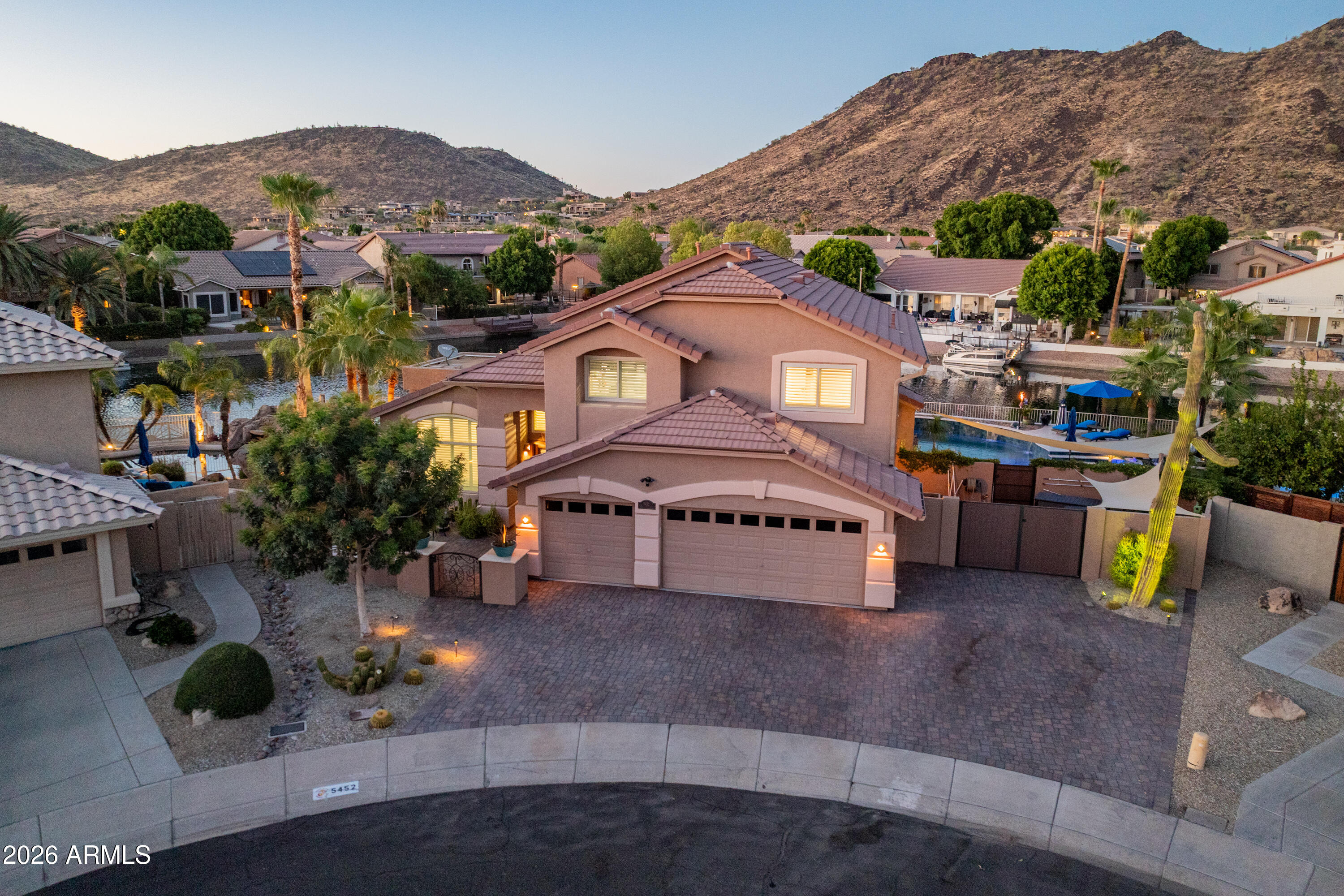 Experience one of the most extraordinary waterfront homes in Arrowhead Lakes! Situated on a rare 150-foot lakefront cul-de-sac lot, this reimagined luxury estate blends resort-style outdoor living with a fully remodeled interior. The backyard boasts a 29-foot masonry BBQ island, custom saltwater pool with attached spa, natural gas firepit, and a stocked pond with waterfall stream and arching bridge. Enjoy sunset rides from your private dock aboard the included pontoon boat, or unwind under automated tiki torches and a full mist-cooling system. The remodeled kitchen features an Italian marble island, and the primary and upstairs baths are fully renovated. All-new flooring runs throughout (no carpet), paired with all-new energy-efficient windows. Additional upgrades include a new roof (2022) whole-house generator, dual A/C units, and Rhino-Shield exterior with a 25-year warranty.