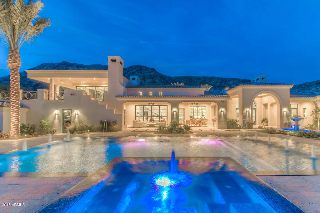 Built in 2016 with panoramic views of Mummy Mtn and Camelback Mtn! Custom details at every turn! White Fossil Stone entrance & patios, grand entry parlor with hand scraped DuChateau European Oak wood floors, limestone fireplaces, soaring beamed ceilings and 8 foot patio doors. Enjoy a Chef's kitchen with butler pantry featuring  barrel rolled brick ceiling, Taj Mahal Quartzite counters, Wolf appliances, limestone vent hood, spacious island with seating, custom cabinetry, and bifold windows with camelback mountain views. 1,000 bottle, all stone wine cellar. Family room and bar/entertainment area features 12' pocket door opening up the home to the gracious views. Grand upstairs patio with outdoor theatre. Private gated auto courtyard, indoor movie theatre, smart home features throughout.