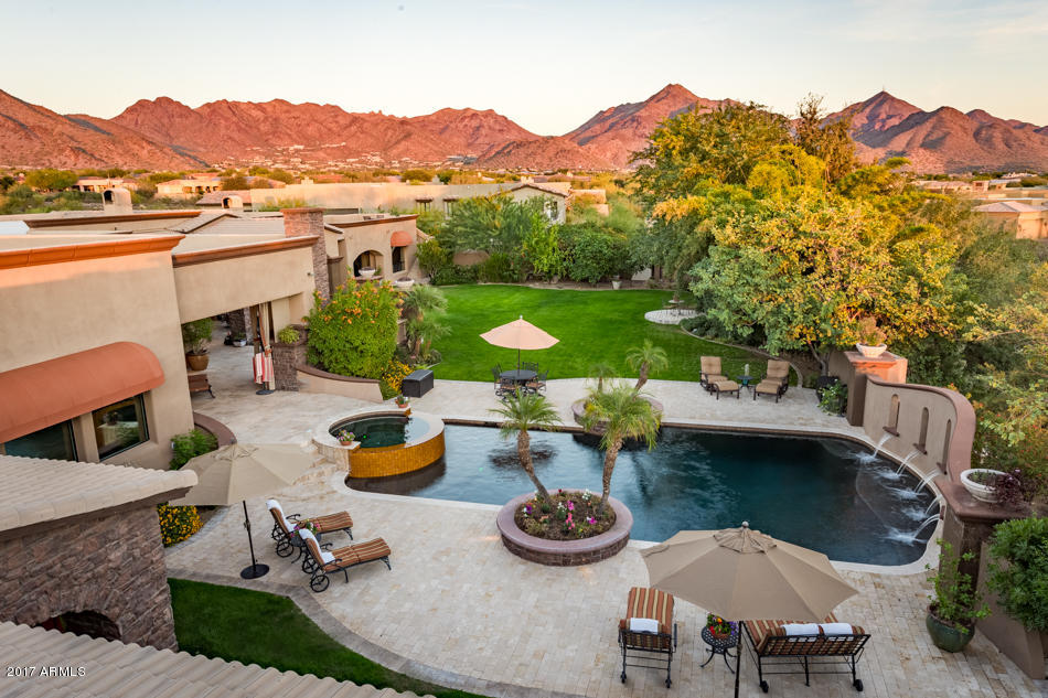 Paradise in Pima acres with panoramic views extending from the McDowell Mountains to Camelback Mountain await from this custom entertainment wonderland on 1.69 acres. Enter through the charming front courtyard with trickling fountain and cozy stone fireplace sitting area.  This magical paradise is nothing short of impressive with dramatic ceilings, grand chefs kitchen, center island & bar seating, living room overlooking the rear grounds, 16 ft floor to ceiling retractable glass doors and indoor/outdoor bar with retractable service area. The split floor plan offers separate guest wing, a private master wing with luxurious master bath, sitting room, exercise area, adjacent office and a detached guest house with kitchen, living and additional bedroom. Private and lush rear grounds The private and lush rear grounds offer multiple outdoor fireplaces, large heated pool & jacuzzi spa with colored lighting, flowing water fountains and pillar-top gas fire pits to illuminate the gorgeous back lawn and entertainment area. Relax by the koi pond, outdoor BBQ and kitchen, pool table area and two roof top viewing decks with 360 mountain and city light views. The oversize and extended RV garage has pet quarters & is also temperature controlled. Truly an outstanding design with comfort, ambiance, amenities and endless views equipped with top-of-the-line entertainment features  truly an entertainer's paradise.