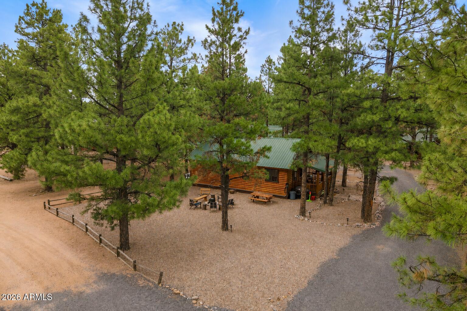 Welcome to your fully furnished mountain retreat! Perfectly nestled among the towering pines on a desirable corner lot in Overgaard's sought-after Bison Ranch community. This beautifully crafted cabin offers two bedrooms, two bathrooms, and an inviting Great Room designed for comfort and gathering. Rich architectural details shine throughout, including wood-paneled vaulted ceilings, warm Hickory hardwood flooring, a striking stone-veneered fireplace accent wall and quality finishes at every turn. The open-concept kitchen is both stylish and functional, featuring custom countertops, sleek stainless steel appliances and abundant cabinetry. The spacious primary suite offers private access to the outdoors and a luxurious en suite bath complete with a copper vessel sink and a custom-tiled walk-in shower with a seamless glass enclosure. Step outside to your landscaped backyard oasis, where a cozy fire pit invites evenings under the stars. Located in the heart of Overgaard, a peaceful four-season mountain destination surrounded by the Sitgreaves National Forest, you'll enjoy cool pine breezes, excellent fishing, scenic hiking and biking trails, and a relaxing escape that's just a 30 minute drive from Show Low, 45 minutes to Pinetop-Lakeside and approximately 2.5 hours from Phoenix.