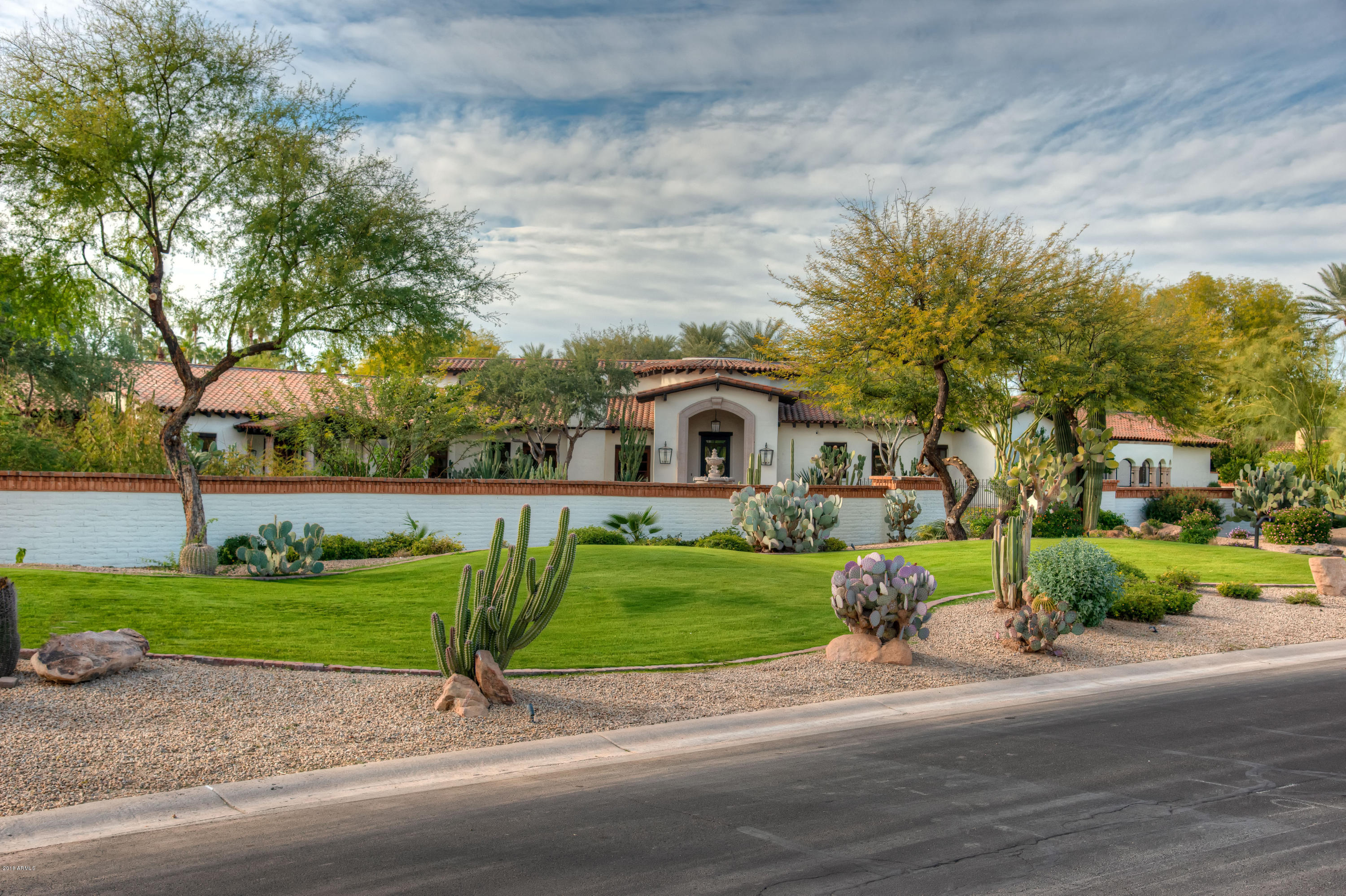 This striking 2-acre estate underwent a massive remodel completed in 2018. The home has a bright, new, transitional feel while keeping the stately heritage from its original block construction in 2002. The extensive remodel mixes a dramatic structure with a beautiful, clean, and comfortable feel. Just about everything, from the roof and viewing decks to the gorgeous limestone and wide plank DuChâteau Antique White wood floors, were replaced, while some of the impressive original custom woodwork was kept in just the right places. MORE.. Upgrades included Cielo custom cabinets and top-of-the-line plumbing in the main home's kitchen, primary, and secondary bedrooms baths. The bright white kitchen offers Subzero-Wolf and Bosch appliances along with a huge dark wood island and butler's pantry off the dining room.  Updated bars can be found in the living, family room, and lower-level game room, in addition to a wine storage room off the living room. The owner's suite is spacious with an exercise room, a private patio with a water feature, two separate closets and commodes, and a stackable washer and dryer.  Fireplaces with new clean line mantels abound.  LED lighting fixtures, cans, and fans were upgraded on the interior and exterior of the home, including the tennis court.
This incredible home includes approximately 10,000 total sq. ft. of exquisitely updated living space, including a 900 sq. ft. casita with living room, bedroom, bath, washer/dryer, and full kitchen, and a 1,200 sq. ft basement with theatre, full bath, and bar. The 4-car attached garage plus a 1,200 sq. ft. detached air-conditioned garage/workshop with office and half bath are a car collector's dream. The resurfaced, recessed tennis court with LED lights, tennis ramada, pool bath, and multiple gated entries make for easy outdoor entertaining, while the lower-level movie theatre and air-conditioned 4 car garage offer indoor options all year long!  The upgraded interior is met by impressive mature landscaping outside and expansive covered patios. Water features abound with a custom elegant fountain as you enter the main gate, a tranquility fountain off the owner's bedroom, and a huge pool with a water feature and outdoor shower off the main home and casita! The home offers both private and well water with a 500-gallon buried tank and home purification. 3C's schools to boot!