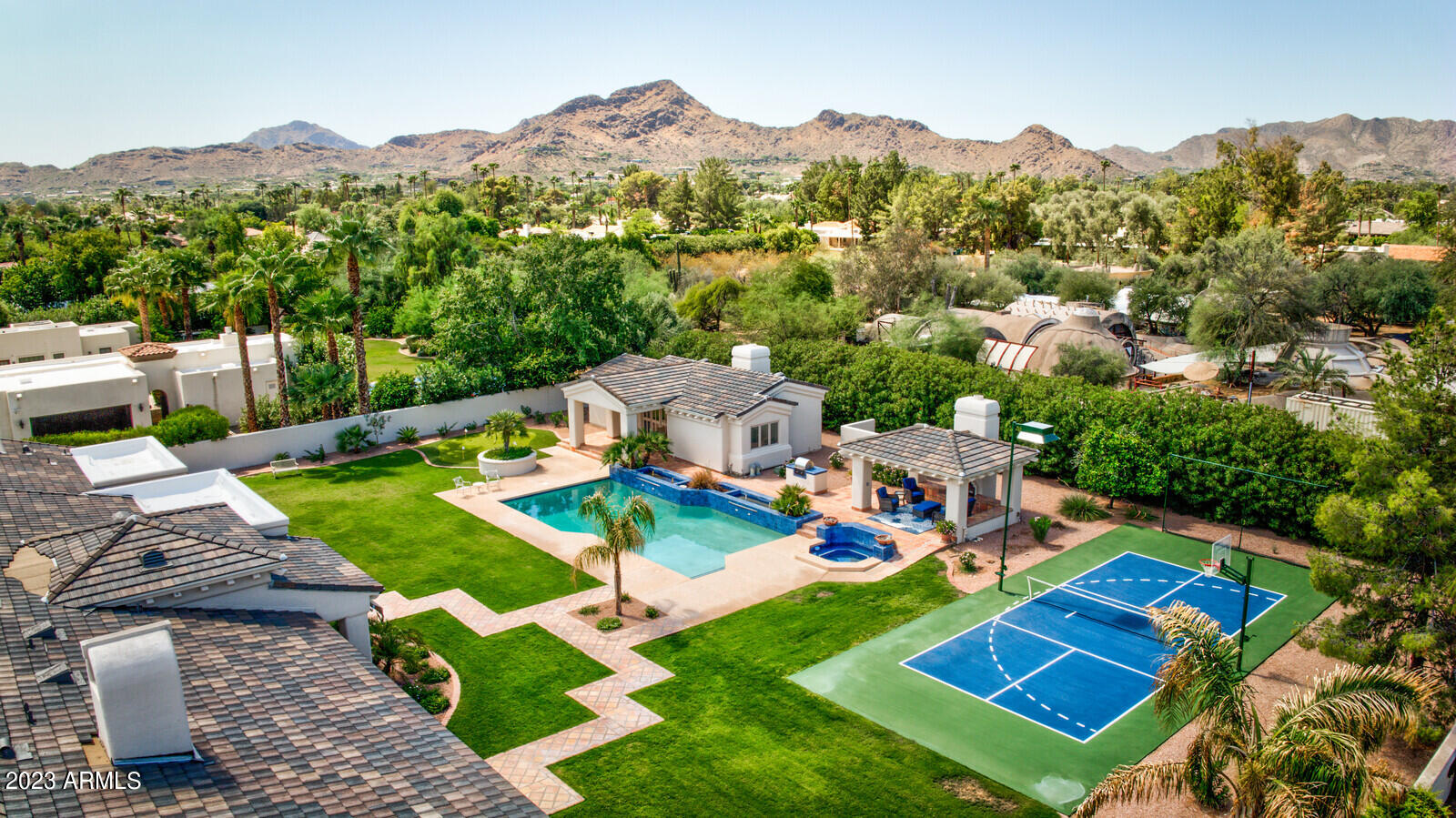 A timeless, beautiful estate in Paradise Valley! This property is sure to impress with its great curb appeal, gorgeous architectural details, high ceilings throughout, wonderful floor plan, guest house, and new roof! Enter the main home and you'll at once appreciate the view straight to the manicured backyard, along with the picturesque custom windows, barrel ceilings, arched doors in primary areas, exquisite 8-ft custom raised panel doors throughout and bright, sophisticated interiors. The elegant dining room is complemented by the office, both spaces containing beautiful arched windows. Kitchen has Viking/Dacor/Subzero appliances, gorgeous cream-colored custom cabinets, an island with prep sink, as well as a charming fireplace and connects with family room. Split floorplan with large bedrooms (all ensuite) including a sumptuous primary suite with large closet and spa-like bathroom. Secondary-bedroom wing has a lounge/gathering space, great for family or guests. Large laundry room has cream-colored custom cabinets, lots of counter space and utility sink. There's also a bonus room with ensuite that can be for nanny, exercise or another office. The spacious guest house is fantastic with fireplace in living room, open kitchen, large bedroom/closet, full bathroom...and a sauna! The backyard is incredible with a huge, heated pool with water features, spa for 8, pickleball court and putting green. Generous ramada with fireplace and built-in gas grill, perfect for watching family and friends play pickleball or swim. This is an action-packed backyard oasis not to be missed. There are 6 fireplaces, tons of storage spaces and a 4-car garage, where the 4th could be a huge workshop. This home is immaculate - owners have taken care of everything so you don't have to: new roof, paint, carpet, pickleball court, putting green, and the list goes on. Main house is 5BD/5.5BA (5th BD/BA is an attached casita) + Office. Guest house is 1BD/1BA/Kitchen/Living. Scottsdale 3 Cs schools. Fabulous location, close to the best shopping and dining in town!