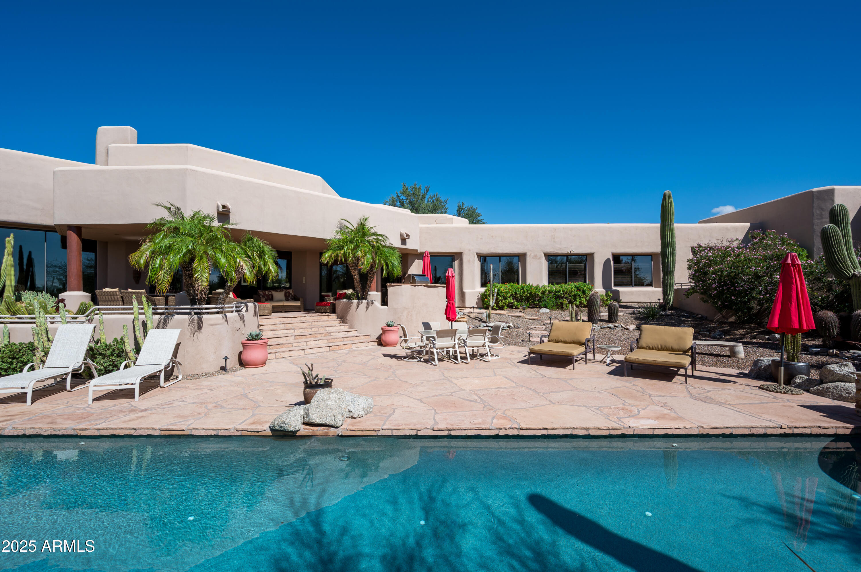 Dreaming of old Arizona when haciendas dotted the lush desert and beckoned to private southwest sanctuaries protected by old wooden gates and rambling stucco walls?  Casa del Sol is that sanctuary at the end of a quiet cul de sac on two lush desert acres framed by the rugged peaks of the McDowell Mountains and Pinnacle Peak. Defining classic and timeless southwest architecture, this territorial home and casita with private entrance harkens back to old Arizona, fleeting in our modern urban sprawl.  FEATURED IN PHOENIX HOME AND GARDEN MAGAZINE years ago as a treasure to be adored, Casa del Sol is for the buyer who craves a timeless, character-rich Arizona territorial defined by its individuality and privacy on 2 lush, beautiful acres.  WELL-MAINTAINED, buy with confidence! With a circle driveway and incredible curb appeal, this home exudes luxury and envelops guests in privacy by welcoming them through ancient wooden doors to a hidden walled courtyard.  A huge cedar door with a friendly, curvy snake iron handle hints at the treasures within and pivots open to inspiring saguaro-studded views across the desert, unfolding like live art in floor to ceiling windows, bringing nature inside.  

DURABLE NATURAL SUSTAINABLE ELEMENTS in flagstone floors, hand-scraped cedar cabinetry, hand-stacked stone, hundred-plus year-old barnwood walls and hand-forged whimsical ironwork stand the test of time.  Items from around the world were creatively employed for functional use inspired by travels to Mexico, Bali, Morocco, India and beyond.  Each space is a study in distant lands and cultures. The floor plan illustrates this architect's vision of a meandering southwest ranch sprawled across acreage, offering surprises around each corner as one travels through this nearly 7,000 SF masterpiece artistically designed for casual and fun living.  

CASA DEL SOL IS IDEAL FOR HOSTING, BOTH LARGE GATHERINGS AND SMALL.  The defined, yet open spaces entertain guests intimately as the architectural design reveals one space at a time with angles and elevations that create separation in the expansive space.  A clear departure from today's modern, wide open white box homes.  

DESIGNED AS A GATHERING HUB, THE CENTER OF THE HOME FEATURES A FUSION OF PUBLIC SPACES: open family room, semi-open kitchen, Moroccan bar, breakfast room, formal dining room and living room turned card room.  Enjoy spirited conversation beneath the grape vine stake ceiling, an after-dinner drink at the MOROCCAN BAR or shuffle a deck in the CARD ROOM.  The dining room offers a stunning view of Pinnacle Peak that is certain to make your guests linger a little bit longer.  Afterward, mosey on down the flagstone hallway to shoot pool in the spacious GAME AND BILLIARDS ROOM, Texas two-step around the corner to the COWBOY BAR for a sip of whiskey or tequila, then sit a spell in the adjacent HOME THEATER'S 12 bright yellow velvet chairs, each row elevated to ensure everyone enjoys the big screen.  This home coaxes out your sense of humor and playfulness.  

GETTING TIRED?  From the theater, play a disappearing act through the bathroom, sneak out the opposite door and enter the attached casita. 

AHHH, THE CASITA!  This 1,000 SF abode has a proper private entrance off the gated motor court, if you don't want to sneak inside.  This not-so-tiny home could make you want to downsize and stay a lifetime.  Perfect for nanny, nana, extended family, or college student, it's fully equipped with living area, bedroom space large enough for a king bed, kitchenette, dining room, stacked laundry, full bath, and its focal point is another one of four stunning stacked stone floor-to-ceiling fireplaces.  Soaring windows frame endless desert vistas and offer mountain views to entice you to visit the secluded private patio where another fireplace beckons.  

TWO GUEST BEDROOMS WITH EN SUITE BATHS are in the bedroom wing, separated from other bedrooms and public rooms.  Each bedroom is large enough to hold multiple beds for hosting several of your smaller guests.  All bedrooms have en suite bathrooms.

THE HOME OFFICE, ADJACENT TO GATHERING SPACES, OFFERS AN ADDITIONAL GUEST ROOM.  If needed, this room could easily be converted to a full bedroom by removing the desk and built-ins, adding an armoire - or a foldaway Murphy bed with storage.

THE OWNER'S SUITE IS IN A PRIVATE WING on the opposite end of the home from guest and activity rooms.  A rewarding destination, it welcomes first into a separate sitting room to unwind from the day cocooned in warmth from another stone fireplace, charmed by a friendly snake twisted around its wrought iron frame.  If you desire a nursery or a second home office, this sitting room will easily accommodate either.  The bedroom shares this whimsical open fireplace, visible from the bed.  Floor to ceiling windows showcase desert flora on sunny days and twinkling distant lights at night.  A private, secluded patio for the owners alone is the best place to enjoy morning coffee or nightcap before turning in.  

BREATHE AND BE TAKEN AWAY TO FOREIGN LANDS IN THE SPACIOUS BALI-INSPIRED BATHROOM with sunken jetted tub for two where candlelight will dance on the flagstone surround.  The dressing room features a mini runway with showroom mirrors to ensure you greet the day in style, and plentiful built-in storage for a multitude of shopping excursions around the world.  Complete with washer and dryer and cabinets designed for a coffee bar.  

THE INCREDIBLE RESORT YARD BECKONS.  After traveling the length of the inside of this territorial masterpiece, step out to the incredible resort backyard - from any room. Every space is connected to the outdoors with floor to ceiling windows and commercial glass doors to capture incredible views of lush, mature desert landscape dotted with native trees and cactus specimens, and provide easy access to al fresco spaces.  

OUTDOOR SPACES EVOKE A BOUTIQUE RESORT.  Patios encircle Casa del Sol offering intimate spaces for quiet moments and grander space for hosting a crowd on multiple levels of timeless flagstone patios. Find your favorite private place to enjoy the sunny climate, read a book, or simply let your mind wander in lush desert landscape views.  The backyard and heated lap pool and spa offer complete privacy. No neighbors can see into your oasis.  Just as enjoyable in the evening when clear skies offer a bounty of magical twinkling city lights of the distant bustling city far below.  

A VACATION HOME for many years, the owners loved sharing Casa del Sol with family, friends and guests who've enjoyed it over the years. Attractive for its spaciousness, ideal north Scottsdale location, interesting and fun gathering spaces, and private bedrooms with en suite baths, all separate from each other.  

FLEXIBLE SPACES AND MULTIPLE EXTRA ROOMS!   The floor plan shows numerous extra spaces with their use defined with furnishings today, yet these rooms could be reimagined in many ways.  Even the gated motor court offers expansion options if desired!  Let your imagination wander!   

Nowhere will you find a home so quintessential Arizona, timeless and defined by its natural beauty, location and unique elements.  Casa del Sol truly is "a home in the sun," southwest-born to captivate generations for decades to come. It's a home for today with so much of yesterday that you may not want to touch it but love it just the way it is.  Escape today's hectic rush and you'll never regret making Casa del Sol your home.  Purchase turnkey, furnished along with its mélange of original artwork and prints in colors coordinating with the interior design, and the magic becomes yours.