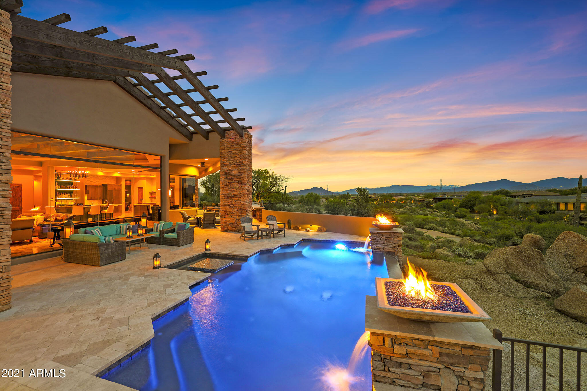Stunning soft contemporary home in gated Talus at Troon North offers spectacular views. The home has been professionally designed with sophisticated, modern features and amenities. Overlooking the 5th Fairway of Troon's Pinnacle course, enjoy panoramic views of the green course, mountain peaks, twinkling city lights & the natural Sonoran Desert. The backyard showcases, not only the views, but a newly refinished pool & spa framing a boulder outcropping, tumbled travertine hardscape, expansive patio spaces for multiple lounging & dining areas, full outdoor kitchen including a Green Egg, burners, sink, storage, pizza oven, barbecue grill, & bar stool seating, fire pit area w/ seating, & putting green. The interior is equally impressive floor to ceiling windows flanking the living room. The living room has hand hewn beamed ceilings, corner fireplace with Basalt stone and metal accents mirroring the exterior stone details, and custom automated cabinetry discreetly concealing the entertainment area. The living overlooks the wet bar and dining area, which features rolled steel accents matching the living room fireplace, kegerator, ice maker, wine fridge, sink, bar top seating and glass light up display shelves. 

 The kitchen is perfect for both entertaining and cooking with matching radius cabinets and counter spaces surrounding the two center islands, both with sinks. The custom cabinetry has smooth lines matched with the white counters making for a beautiful contrast. The stacked stone backsplash, custom metal hood vent, stainless steel appliances from Wolf and Miele including a coffee maker, two dishwashers and 6-burner gas stove with griddle. Adjacent to the kitchen is the keeping/wine room with a 536-bottle wine cellar glass front display. 
(
Sleeping quarters throughout the home include the large master suite with fireplace, sitting area, wet bar, marble clad bathroom with massive shower, freestanding tub, separate sinks, vanity, and two California Closet designed spaces for optimal closet organization. Two additional guest rooms include one ensuite and one adjacent to the guest bath. There is also another guest bath with exterior access. The detached guest casita with grand entrance and kitchenette complete the sleeping spaces for a total of four bedrooms and five bathrooms. 
(
A private office with built-in bookshelves, movie theatre space with elevated seating, bar, and automated shades over the windows allowing for complete privacy, and a large laundry complete the interior spaces. The four-car garage is separated into two stalls each on either wing of the home. A complete smart home system is included which includes operation of the smart shades, speakers throughout, pool, and heating/air, all controlled through the Creston system. 
(
Other features throughout include: restoration hardware light fixtures; Minka fans; custom shades and curtains throughout; travertine stone, ceramic wood tile, and designer carpet flooring surfaces; solar heat for the pool; Venetian plaster; and 6,349 square feet of living space. Most furnishings available by Separate Bill of Sale.