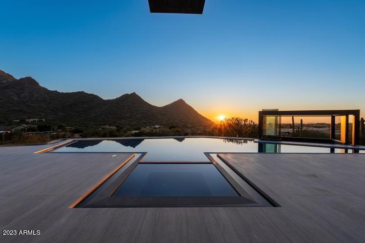 The life of luxury awaits in one of the most prestigious and sought after gated communities in North Scottsdale! This gorgeous multi-level 11687 sq ft modern contemporary estate found at the end of a cul-de-sac lot is a hidden gem of the desert. This 6 bedroom, 7.5 bathroom home is an oasis with unparalleled views of the Sonoran desert below. Meticulously thought-out design includes a resort style entrance, interconnecting ''coastal look'' water features, top-of-the line appliance package, a 4-car garage, custom doors and cabinets, a personal gym, and a perfect media room space. The custom high end open kitchen comes with garage style electronic door to allow the outdoors in! The main primary suite includes a private living room, full wet bar, kitchenette, two closets, built-ins, floating The custom high end open kitchen comes with garage style electronic door to allow the outdoors in! The main primary suite includes a private living room, full wet bar, kitchenette, two closets, built-ins, floating bed, and a fireplace with a pop up tv, electric windows that open up or down, private balcony and outdoor shower. The primary bathroom includes a large soaking tub with a gorgeous view and a luxurious 3 rain shower head. Downstairs features an oversized ensuite with a walk-in closet, free standing tub and a private balcony with views. The backyard is an entertainer's dream with a full-size tennis court, waterfall pool, jacuzzi, outdoor wet bar, retractable roof, outdoor TVs, outdoor showers, sunken fire pits, and direct access to a private bathroom. Poolside offers a 300 sq ft enclosed cabana with retracting roof and sliding widows.  Guests will enjoy the 900 sq ft guest house, upgraded to match the luxury of the main house. High-end luxury meets calming oasis. This home has it all and more!!