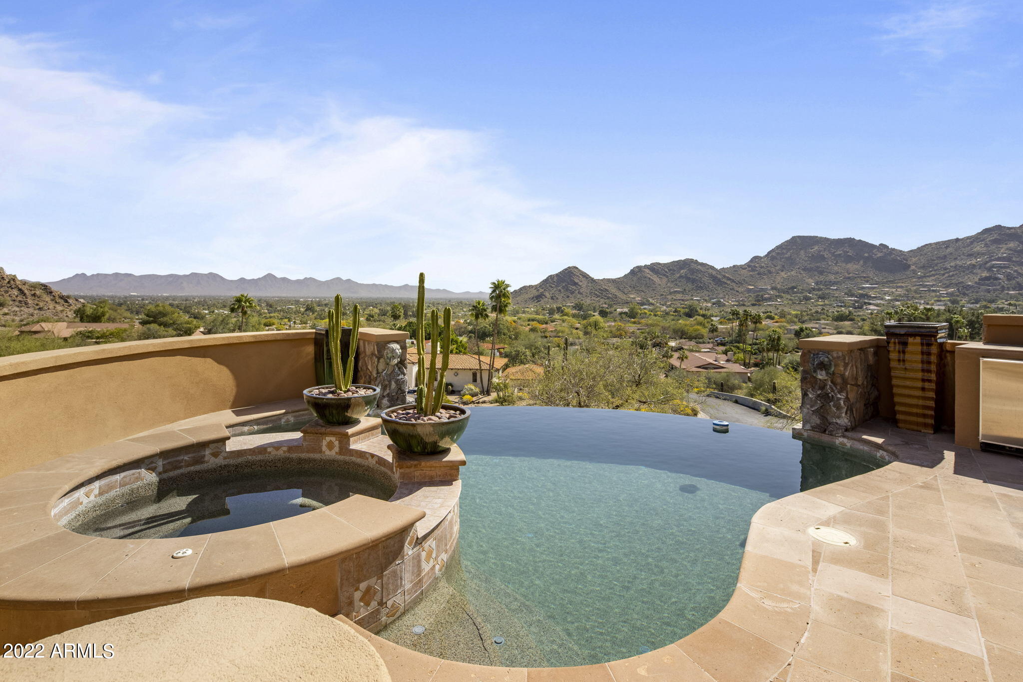 Timeless hillside estate with unrivaled views reaching from Camelback and Mummy Mountain all the way to Pinnacle Peak. Custom built with no detail spared. This exquisite property really has it all including a grand stairway entrance, beautiful foyer over looking a one of a kind hillside waterfall, 5 spacious bedrooms, elevator, wine room, formal office with custom built-ins and game room with wet bar. Travertine and Alder wood floors throughout the home. Gourmet kitchen that opens to family room and breakfast nook. Stunning owner's suite with panoramic views, sitting area with fireplace, two oversized clothing closets, beautiful bathroom, steam shower and a bonus space that would make for a wonderful home gym or massage room. The lower level also features guest quarters with kitchen and home theater. The spectacular negative edge pool with jacuzzi is the perfect spot to relax and enjoy sensational AZ sunsets.