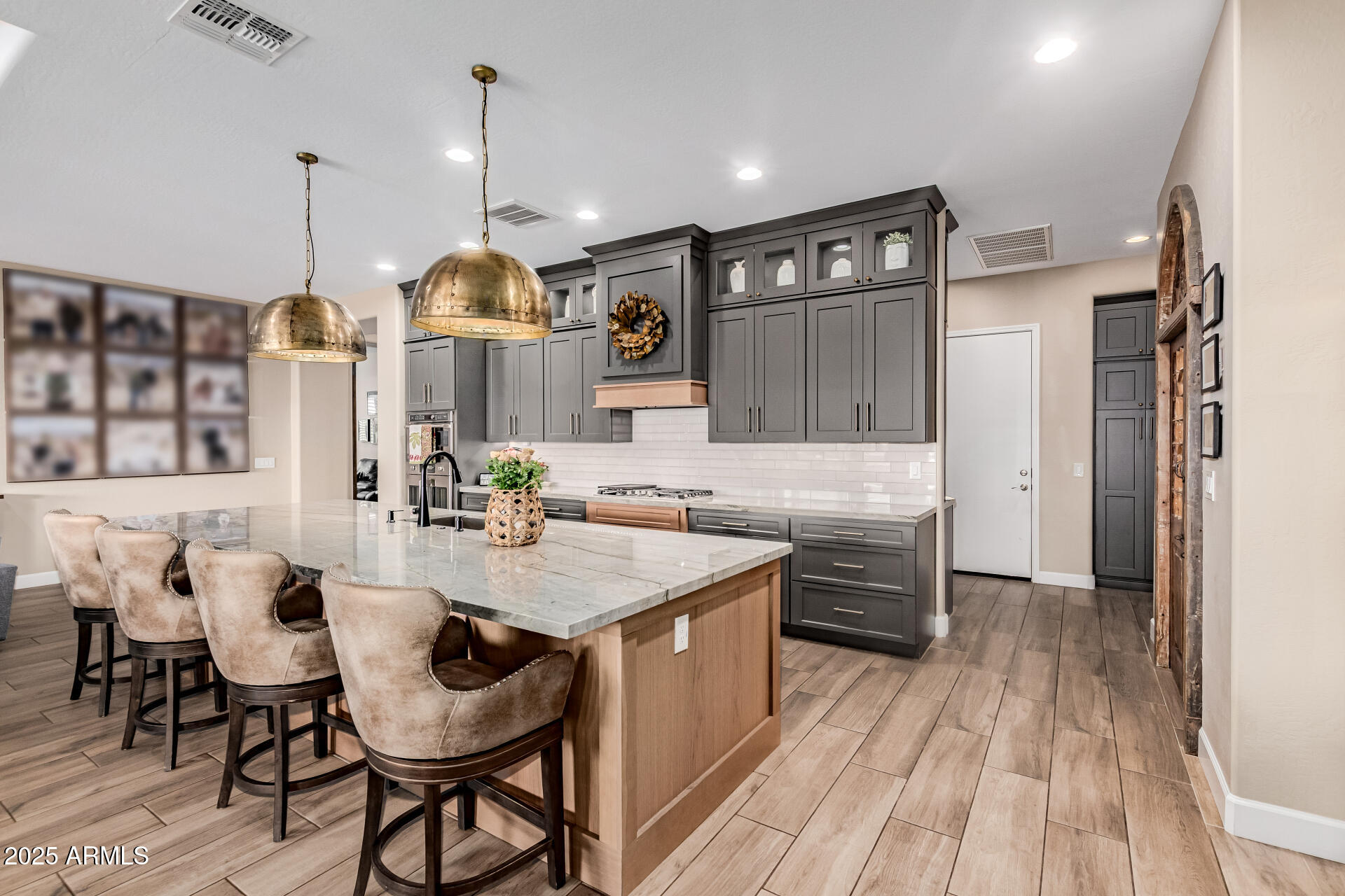 PRICE IMPROVEMENT!  Must see, David Weekley Celebration model in Victory at Verrado--a move-in-ready home where every detail has been thoughtfully reimagined. Built in 2019 and extensively updated in 2022, this beauty features wood-look tile flooring, a chef's kitchen with expanded custom pantry and designer door, coffee bar, upgraded cabinetry with lighting, quartzite counters, and Sub-Zero refrigerator. The great room showcases a custom entertainment wall with fireplace and built-ins, while tray ceilings add elegance. Each bedroom offers its own bath, and the primary suite includes California Custom Closets. A study, bonus retreat, and private backyard with pool, outdoor kitchen, firepit, putting green, retractable sunscreens, and OWNED SOLAR make this home truly exceptional.