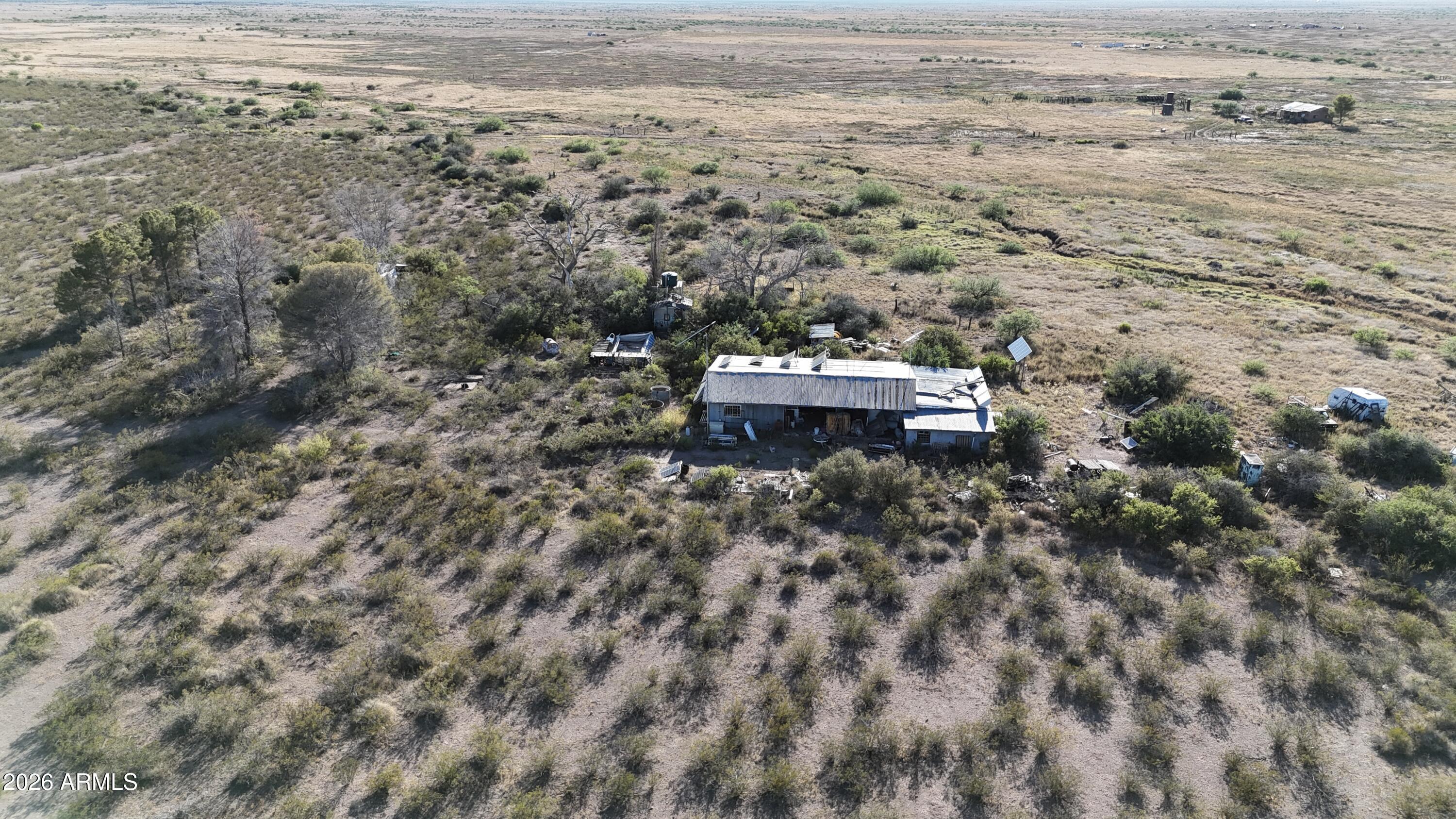 28-acre rural property featuring mountain views, a private well, solar panels, inverters and battery storage, an older workshop, and a 20' x 30' apartment constructed of insulated concrete block. The apartment includes radiant floor heating, a kitchenette, and a bathroom with a shower and sink. This is a significant cleanup project and is not for the faint of heart. 
The property may appeal to buyers seeking acreage, a workshop, salvage opportunities, off-grid potential, or a project property with existing improvements. Extreme caution is advised during all showings. The site contains overgrown areas, debris, abandoned vehicles, active hornets and bee activity, and potential wildlife hazards including snakes. Access is via rural roads that may become muddy and difficult to navigate during monsoon season. Four-wheel-drive vehicles are recommended during wet conditions.
If you're looking for a turnkey property, this is not it. If you're looking for usable acreage with a private well, solar power, mountain views, a workshop, and a solidly constructed apartment with the opportunity to create value through cleanup and rehabilitation, this property deserves a closer look.
This property is being sold strictly AS-IS and includes all remaining personal property, vehicles, equipment, scrap metal, debris, and miscellaneous items currently located on the premises. Buyer will be responsible for any cleanup, removal, or disposal after closing.