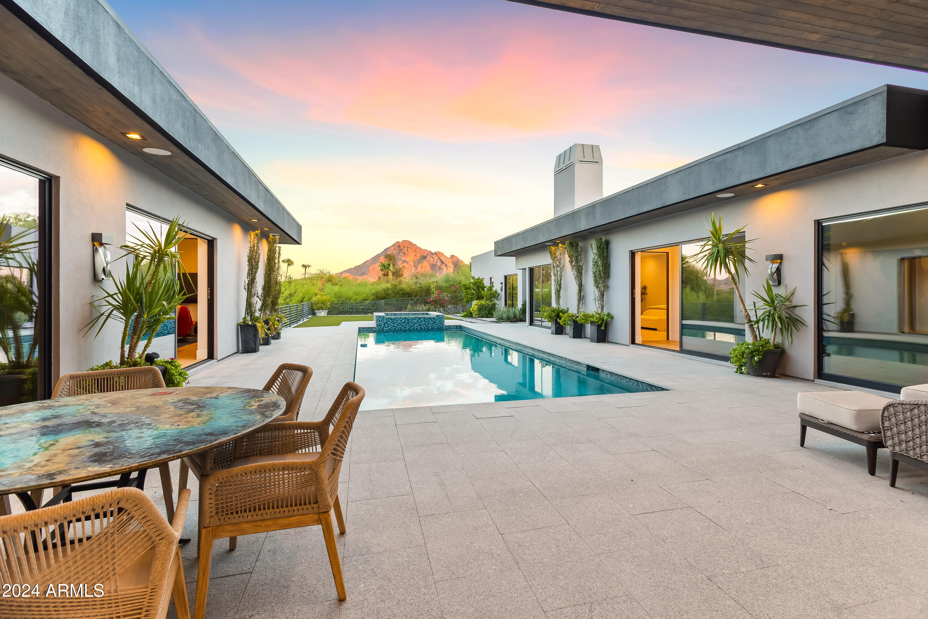 One of the most unique homes in Paradise Valley. You pause as the private gate opens revealing the stunning entrance framed by two custom fountains.  As you open the incredible hand crafted front door you are overwhelmed by the view from the large. Courtyard. This meticulously well maintained home with lush landscaping offers alfresco dining alongside the sparkling  20' lap pool and spa. focusing directly on Camelback Mountain. Fourteen foot ceilings reign over the large sliding glass windows which disappear into the walls with the push of a button. This house was created for indoor outdoor entertaining. The kitchen, a chef's dream features Gaggenau appliances, a 6x11 soapstone island with Paul Henningsen's Artichoke Lighting above also includes a well appointed butlers pantry. The open kitchen concept embraces a spacious family room and inviting breakfast nook with corner fireplace. Massive exotic Tiger Wood barn doors are featured in the two en-suite guest bedrooms. Virtually every room captures our magical Arizona lighting and views from nearly every room of the three iconic mountains, The Preserve, Mummy and Camelback. Two separate offices, one with distinctive large fireplace  allow more than one person to work while home. At the end of the courtyard visit the entertainment room or stay in shape with the private gym adjacent to the large self contained Casita. The air conditioned 3 car garage has additional storage for bikes and holiday decorations. Privately positioned with easy access to AJ's, Global Ambassador, Steak 44, Paradise Valley Country Club and PCDS. Minutes to Phoenix Airport, HWY 51 & 101.