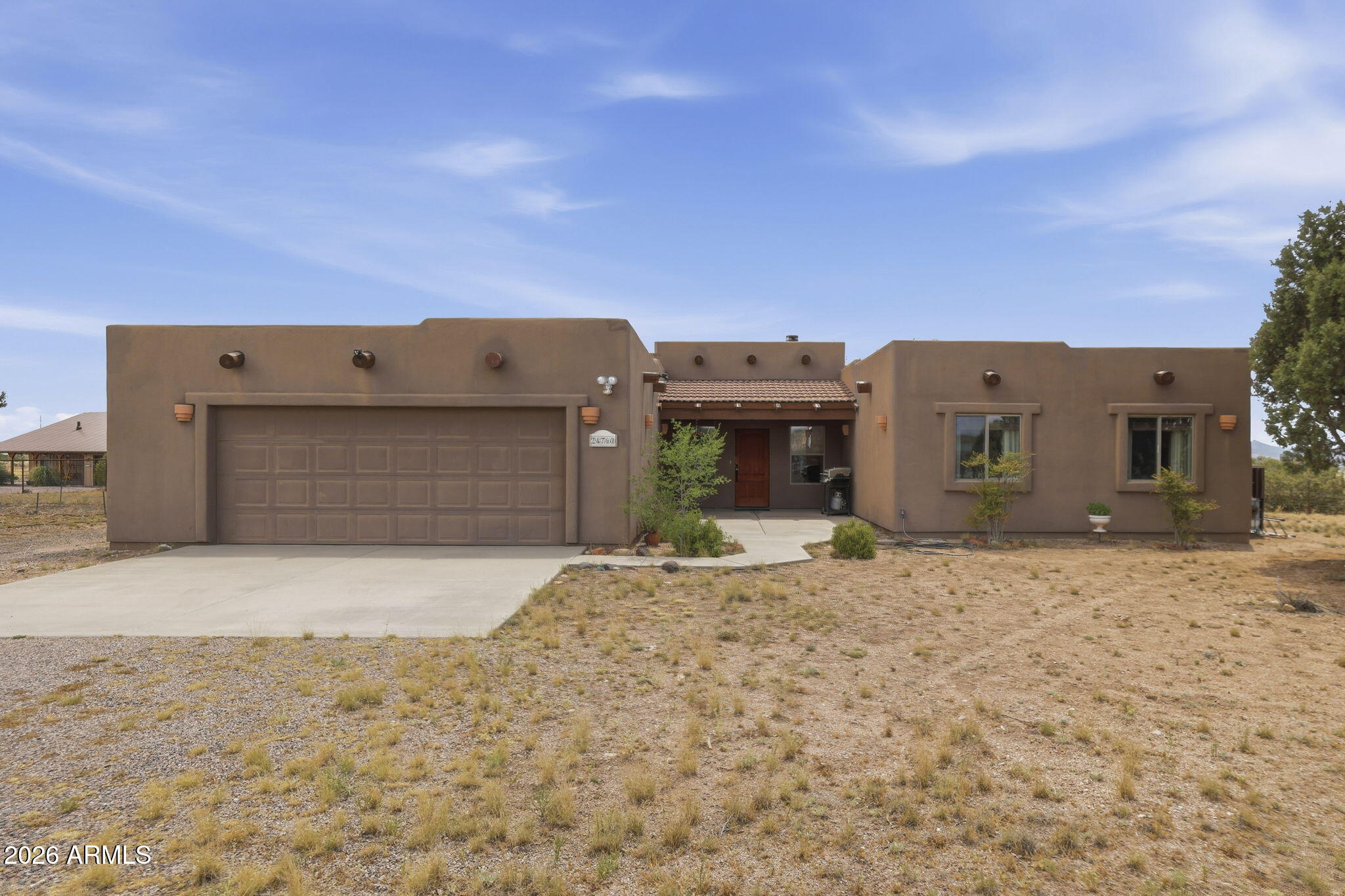 Welcome to wide-open views, Southwestern charm, and peaceful country living come together beautifully. This well-kept home features an inviting open layout with tile flooring, wood accents, a cozy stone fireplace, and plenty of natural light. The spacious kitchen offers abundant cabinetry, generous counter space, gas range, breakfast bar, and scenic views from the sink. The primary suite includes patio access, dual sinks, soaking tub, and separate shower. Outside, enjoy a gated entry, fenced acreage, covered back patio, mature trees, attached garage, and panoramic mountain views. Bring your animals, toys, or love for quiet Arizona sunsets. This one has space, warmth, and room to roam.