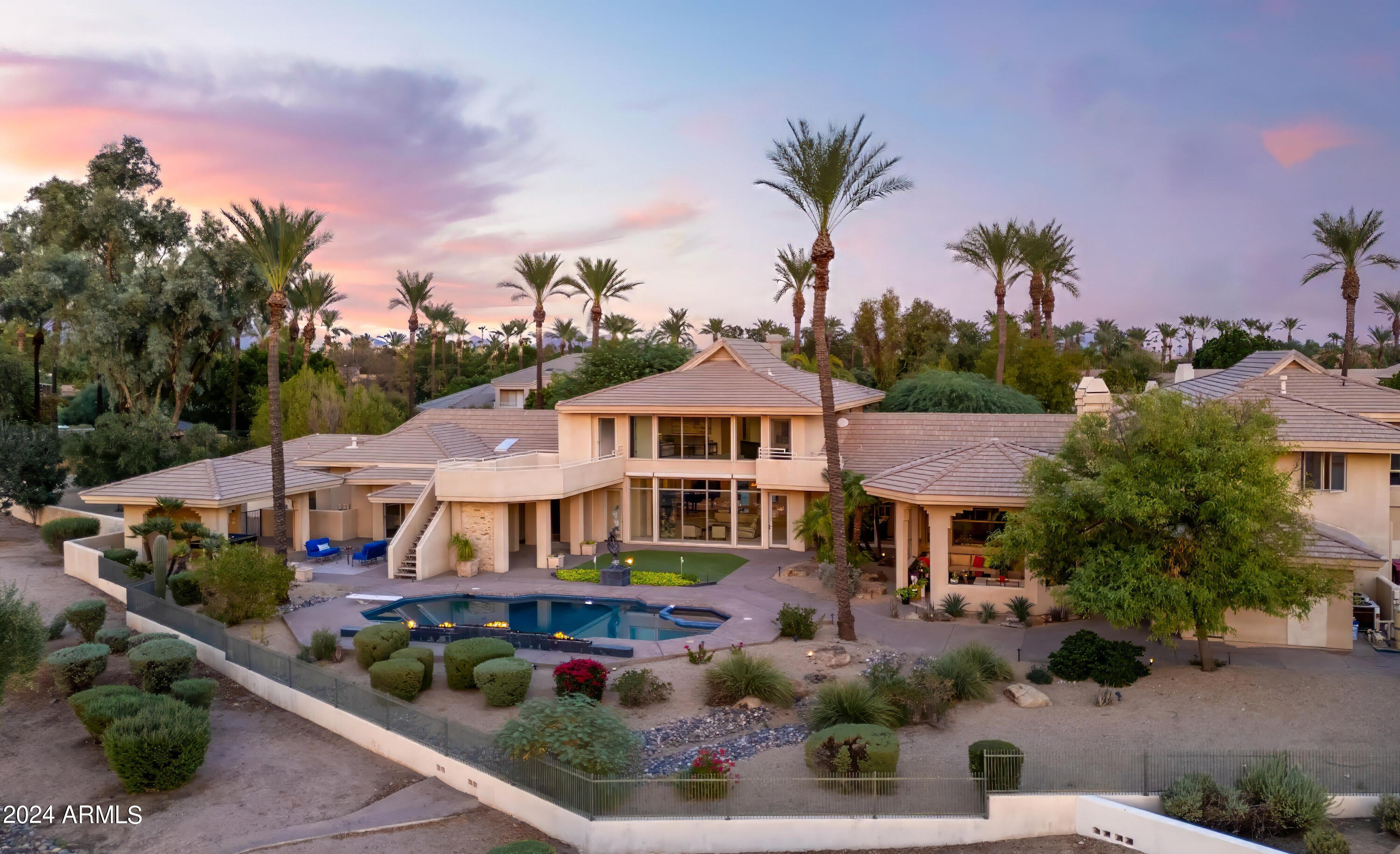 Welcome home to Gainey Ranch - A guard gated oasis of lush vegetation, convenient shopping, a variety of dining, 27 holes of golf, and active lifestyle amenities such as an indoor gym, sports courts, and a lap pool, all at your doorstep. This gated estate is perfectly situated along the Arroyo golf course on an acre lot, with panoramic golf course and Mummy mountain views. Perfect for car collectors or large families, this home features an 8-car garage (all w/ room for lifts), an attached guest casita with 3 bedrooms and kitchen, as well as a kids wing with 3 ensuite bedrooms, ideal for multi generational living. As you enter the home, a wide wall of floor to ceiling windows draws your eye out over the sparkling blue pool to gently rolling emerald fairways. The expansive layout with bright, airy rooms, offers a variety of living and entertaining options: from the intimate private office, to separate wings for children and/or guests, to the sprawling formal living area, to the cozy open floor family/breakfast room and kitchen. Enjoy the primary rooms' elevated, unobstructed view of the luscious golf course and rugged mountains. The primary suite encompasses a large bedroom, sitting area, wet bar, laundry room as well as His & Hers closets, His & Hers bathrooms, His & Hers showers, AND His & Hers vanities. With easy access to premier amenities, matched with a unique yet highly desired layout - this spacious home embodies Scottsdales vibrant lifestyle full of luxury and leisure.