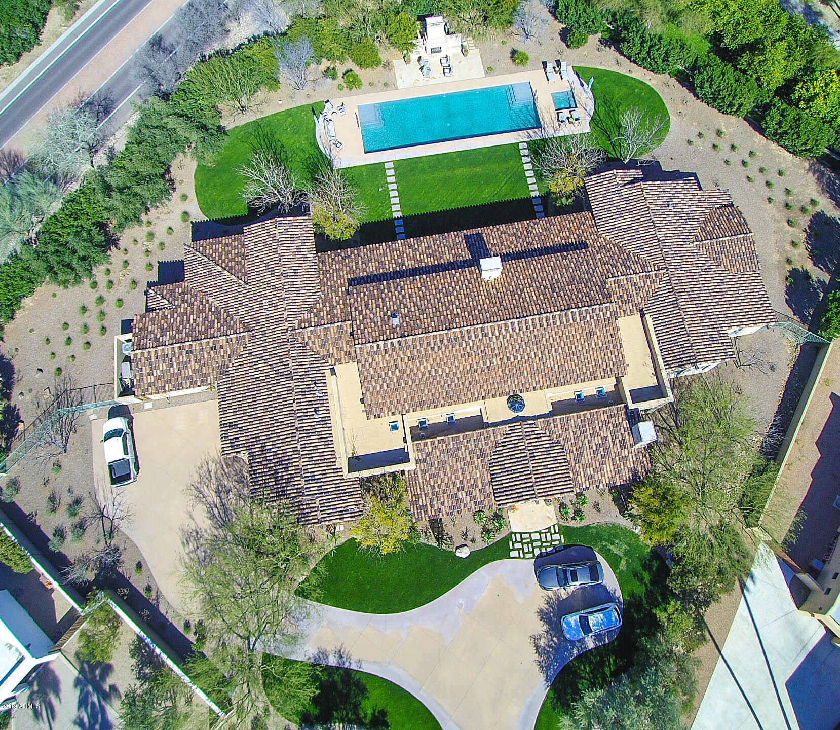 From the moment you enter this masterful custom estate, it's clear this is far from ordinary in every detail. The refined rustic ranch hacienda style is perfect for the extreme Arizona desert climate. Designed with deep portals, soaring 15ft ceilings, and extensive windows and French doors to provide maximum outdoor enjoyment and welcomed shade for rest and social gatherings.
The finest custom finishes include imported exterior and interior stone, solid limestone floors laid in an elegant herringbone pattern, and custom French-bleed hardwood floors. Solid wood ceiling beams were hand finished on-site by the finest craftsmen, 7 inch crown molding and 5.5 inch baseboards. Exceptional stone, glass, mosaic transitions, and backsplash finishes are throughout the vestibules, bathrooms and hallways.
The hand-carved 5.5 ft. stone fireplace is topped with a one-of-a-kind 8ft hydro-pressure treated, solid slab cherry granite inset flanked by several 9ft French doors that open to the expansive patio.  Truly no expense was spared. 
Charming and inviting spaces from the formal living room and dining room, vestibules and 9 ft hallways lead to a truly great room with welcoming space for any size social or intimate gathering. The chef's kitchen has a luxurious 15 foot butcher block island with multiple work surfaces, dual ovens, wine and beverage fridges, ice maker, everything needed to entertain â€“ including an extensive butler's pantry, catering workspace, and chef's office. 
The east wing master retreat with French doors leading to a refreshing covered patio and pool is strategically placed for overlooking the fabulous Mummy Mountains views. Double walk-in closets, custom vanities, gorgeous soaking tub and even it's own washer and dryer. 
The west wing has flex space for unlimited options for a massive home office/study, entertainment room or 2 additional bedrooms with en-suites plus office (architect plans available.) The space was created and prepared with various future options in mind. 
The backyard oasis has lush mature landscaping with 12ft hedges for a secluded, yet open retreat to enjoy the enormous heated 1100sf lap pool, heated spa, and massive outdoor stone fireplace. Perfect for relaxing or entertaining, day or night. Check out the recent sale down the street at 8100 N 68th St closed 3/7/2019 for $12,000,000, $670sf.