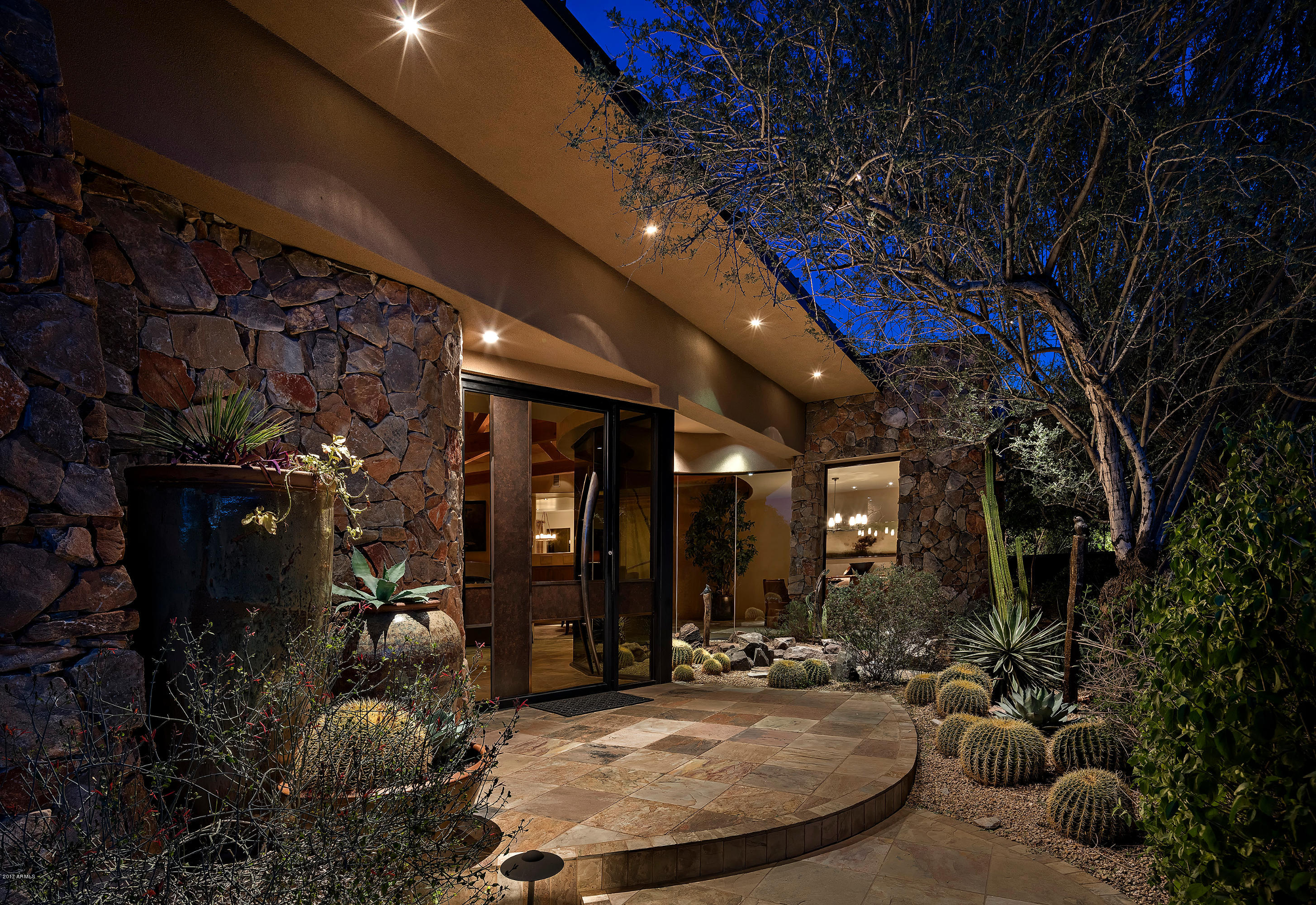 Warm and inviting with a touch of contemporary, this beautiful home located in Scottsdale’s private and guard-gated  neighborhood, Lost Canyon, exudes a private resort style setting taking full advantage of its gorgeous 4 + acres of pristine desert, complete with your own private wash, boulder outcroppings, some of the finest city light & mountain views available, and it all comes turn-key which includes ALL furnishings.
Upon entering you immediately notice the marriage of home and desert with beautiful glass walls that extend into the foyer, perfectly framing a stunning pond feature that is also in perfect view of the formal dining room, adding yet another beautiful level of ambiance of bringing the outdoors in. Your guests will have all the space and privacy they need, with 4 full suite with private patios and access to the pool and spa. For even more room enjoy a study with gorgeous built-ins, an exercise room, and guest bedroom. Enjoy the seamless indoor-outdoor entertaining with your chef's kitchen w/ 3 ovens, top-of-the line appliances and wine cooler, kitchen room, formal dining room, gorgeous wet bar with amazing views,  grand living room with fireplace, high wood-beamed ceiling,  and large retractable doors that let you continue the entertaining to the outdoors all the while taking in the desert landscape. Also for your entertaining enjoyment, attached to the garage is an enclosed garage bay/man cave complete with shuffleboard and plenty of space for getting away.

Enjoy your own spa like private retreat with this gorgeous master with his and her closets, cozy fireplace and sitting area, beautiful mountain and boulder rock views with access to your backyard oasis, and all the while maintaining privacy. The large master bath is like having your very own spa, complete with large resort style vanities, large shower, jetted tub and steam shower.

Outdoors the perfect resort style setting, complete with stunning mountain, city light, desert and boulder views, the perfect back drop to entertaining at its finest. Enjoy a negative edge pool with waterfall, spa, multiple fireplaces and fire-pit, and lots of space for dining and entertaining.