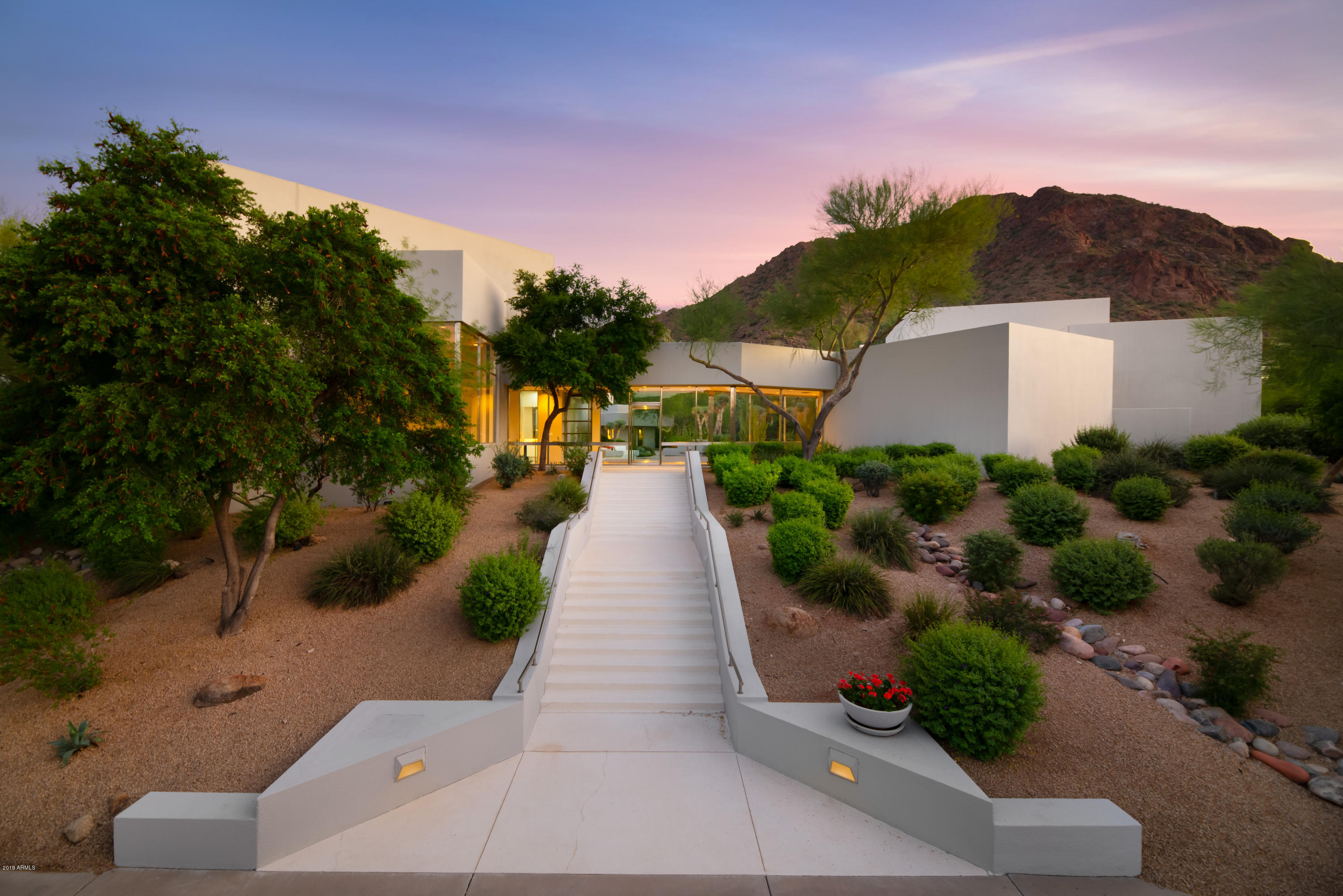 This exquisite gated contemporary estate sits on 4.5+acres with stunning mountain views. A true masterpiece that is second to none and radiates style and design. Floor to ceiling glass windows boasting the natural Desert beauty of Camelback Mountain. This is the perfect entertaining home with a dining room featuring electric privacy doors and wet bar. Expansive master suite featuring an adjoining office, workout area, sauna and steam room. The master bathroom includes two of everything: clothing closets, water closets, vanities, shower and a deep soak tub. The upstairs den/office has ample built-in storage space and panoramic views looking over all of Paradise Valley. Spacious 2 bed, 2 bath guest house, with living space and kitchenette, over looks the tennis court, pool and water feature.
