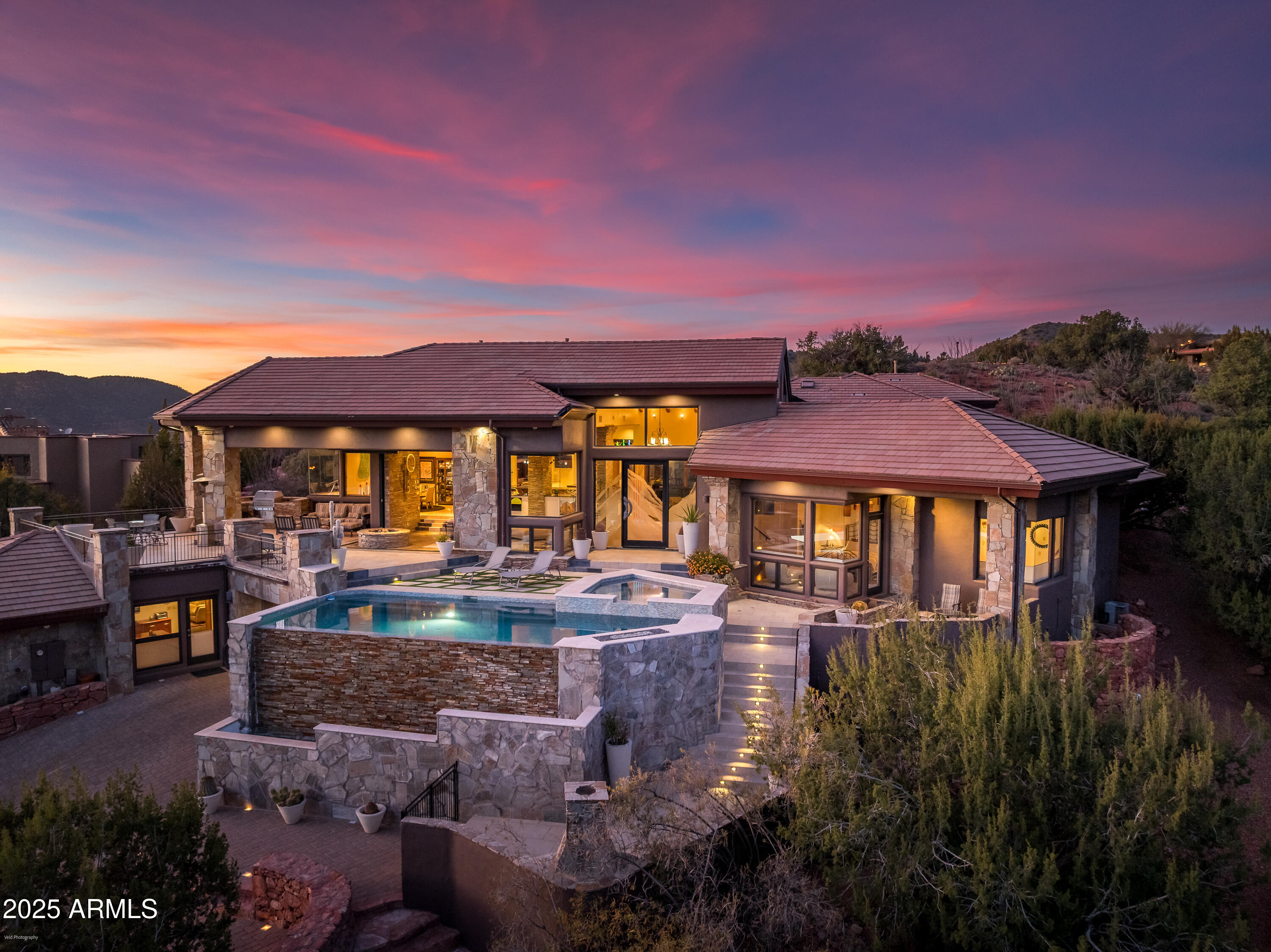 Exclusive top of the hill location with knockout panoramic red rock views and expansive indoor/outdoor space with elevated views. Within the luxury gated community of Back O Beyond, this Modern, luxury contemporary home offers separate guest accommodations and a showcase 7+ car garage. Ideal for entertaining, this home has a massive kitchen/living room with telescoping doors opening onto the outdoor kitchen, living room and Pebble-Tek pool and spa. Enjoy Sedona's mild seasons from the elevated patio with outdoor living space, plus pool and spa directly facing Cathedral Rock. Lower level attached casita gives your guests privacy and luxury from the 2 bedroom suite including  temperature controlled 1200 bottle wine storage. Main level = 4400 sq ft 
Massive open kitchen with stainless appliances, radius island, additional refrigerator drawers and two dishwashers. 
Music/Media room walks out onto the rear patio
Primary bedroom suite with soaring ceilings faces Cathedral Rock view instant morning views
Two additional guest suites plus powder room, laundry room, formal dining room round out the upper level.  
Garage
Showcase car collector garage with space for 7+ vehicles and workshop or studio space could also be optimized for a home gym. 
Lower level = 1905 sq ft
9' ceilings in the lower level - two separate entrances plus garage access.  Wine storage space for 1200 bottle collection is temperature controlled.
Two bedroom suites plus an additional living room will make your guests feel comfortable yet private from the main living space.