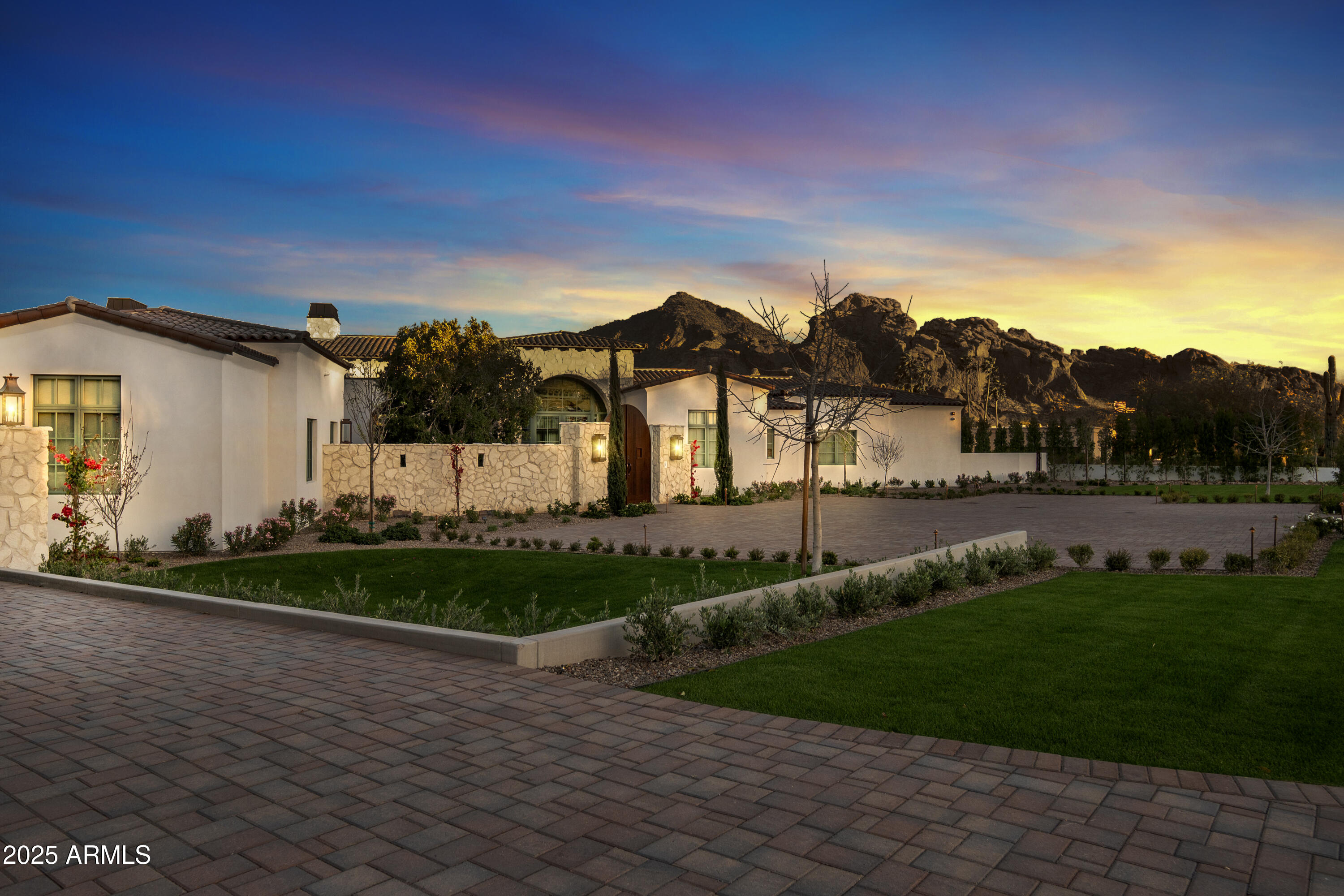 Casa La Roca, another single-level masterpiece estate built by DNP Homes, a stunning Mission-style estate set on a next-level Paradise Valley view lot. The breathtaking views of Camelback and Phoenix Preserve are prominently secured here; guests can elegantly be greeted within a zen-friendly gated courtyard before entering through its 16-foot arched glass entryway. Designed for entertaining, highlights include a 50-foot infinity-edge pool, a back kitchen, a walk-in wine room, and a state-of-the-art smart home system. The owner's wing boasts spa amenities like a steam room, private patio and boutique-style show closets. We welcome you to examine its craftsmanship, see its hand-chiseled stonework, Italian imported fixtures and finishing materials that'll define its value. Complete with a 4-car climate-controlled garage, this residence epitomizes elegance and modern convenience.