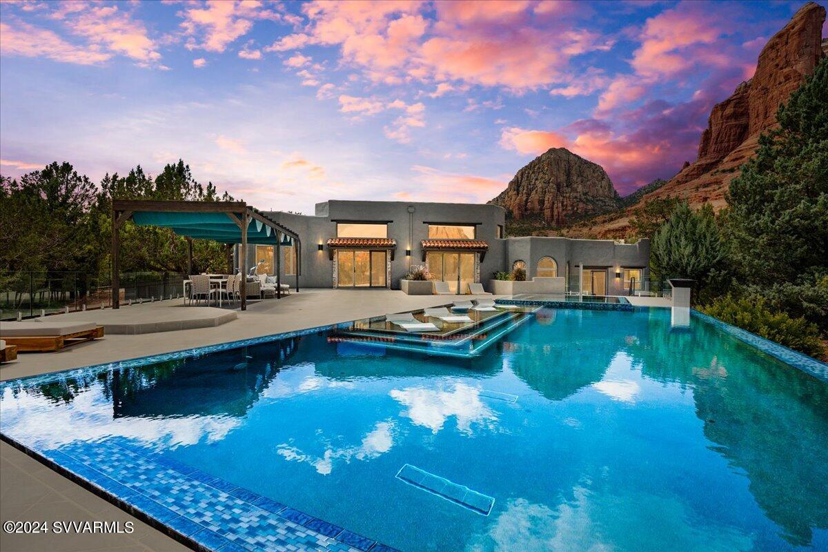 Prepare to be enthralled. Absolutely amazing home offers breathtaking views & an incredible salt water swimming pool, spa & patio outdoor living space. Sound healing in an expansive spa & negative edge swimming pool with waterfall, outdoor shower and fire features too. Custom built Hacienda style estate on nearly an acre with inviting entry courtyard, open ceilings & tasteful, modern upgrades throughout. Tucked at the end of a quiet cul de sac & resting on its own knoll; creating a feeling of forested privacy & intimacy with the dramatic, red rock views! This magical home includes five bedrooms plus an office, & guest wing including a separate entrance, kitchenette & a private 
 SW hot tub  patio too. This enchanting property  and home is one of the finest in Sedona and is a must see.