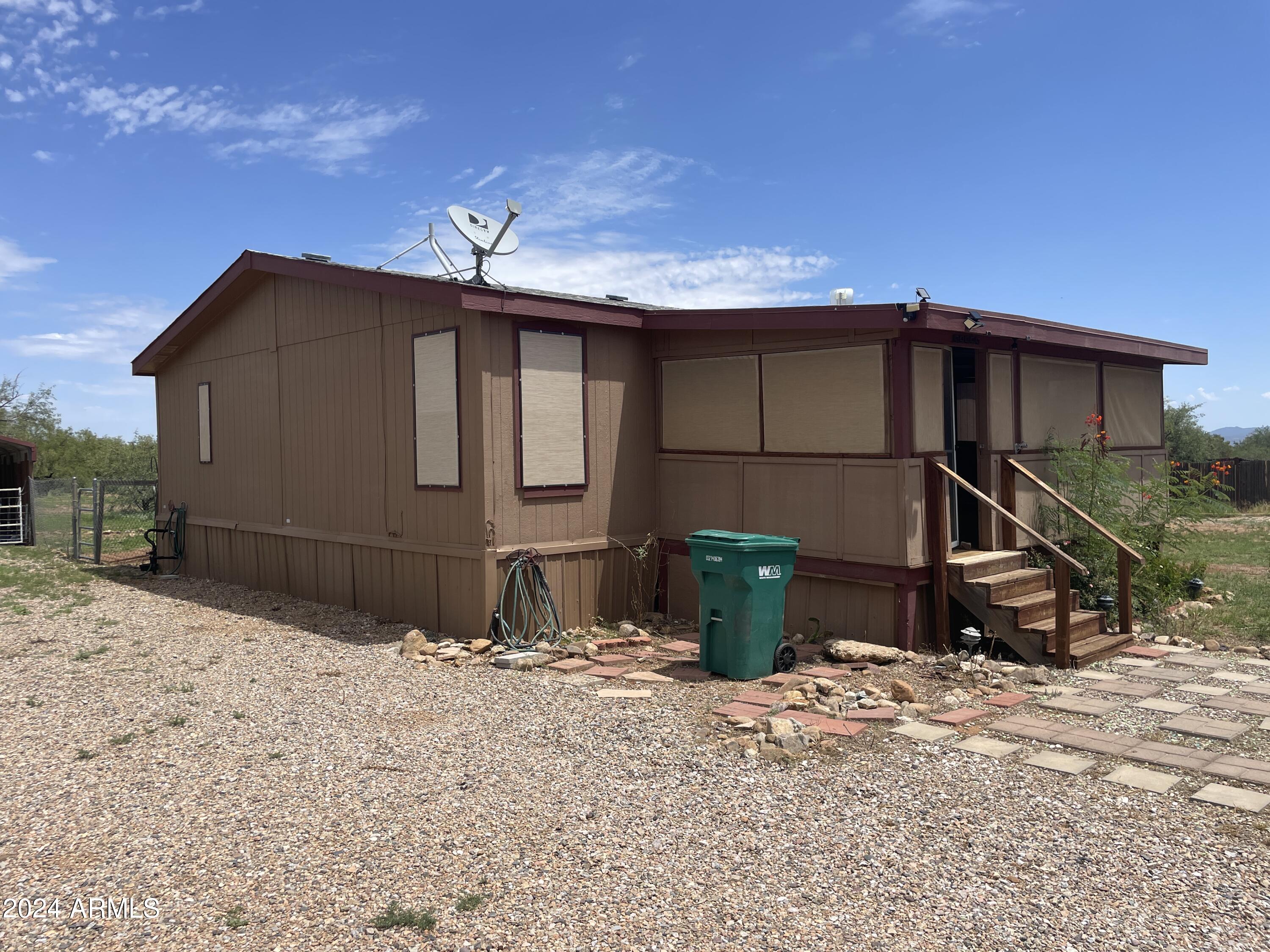 Peaceful country living with beautiful mountain views and over an acre of land!
This 3 bedroom, 2 bath, split floorplan home is ready for new owners! Large screened in front porch allows you to enjoy the beautiful Arizona weather all year long. New flooring throughout, new paint, spacious living room and large primary suite. Sunscreens on all the windows, large ramp off the back of the home leads into a fenced in backyard with 2 storage areas and a carport. Do not miss the opportunity to call it HOME!