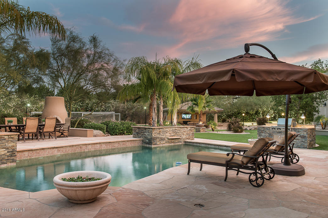 Nestled on a corner lot in the shadows of Mummy Mountain…this custom built 6432 sf home sits on 1.56 magically landscaped acres. With more than $500,000 in improvements, this estate misses nothing. Flowing lines and spacious windows allow for abundant sunshine. Split floorplan with master wing includes his and her offices or flex space for workout room. Vast formal living room opens to the wondrous backyard for the ultimate in indoor/outdoor living.  Open great room concept with chef’s kitchen and separate butler’s pantry with ice maker and warming drawer. Enjoy the best of the outdoors with expansive flagstone patios, pebble tec pool w/ sheer descents, fire pot accent features and separate sitting areas each with gas fireplaces.   Football games, soccer practice, banquet receptions – all can be easily accommodated on your own field!  Top of the line synthetic turf with it's own watering system keeps cost down and the beauty abundant!  Outdoor ramada with misting system, beverage center and wet bar top off what can only be said as one of the prettiest yards in PV.
