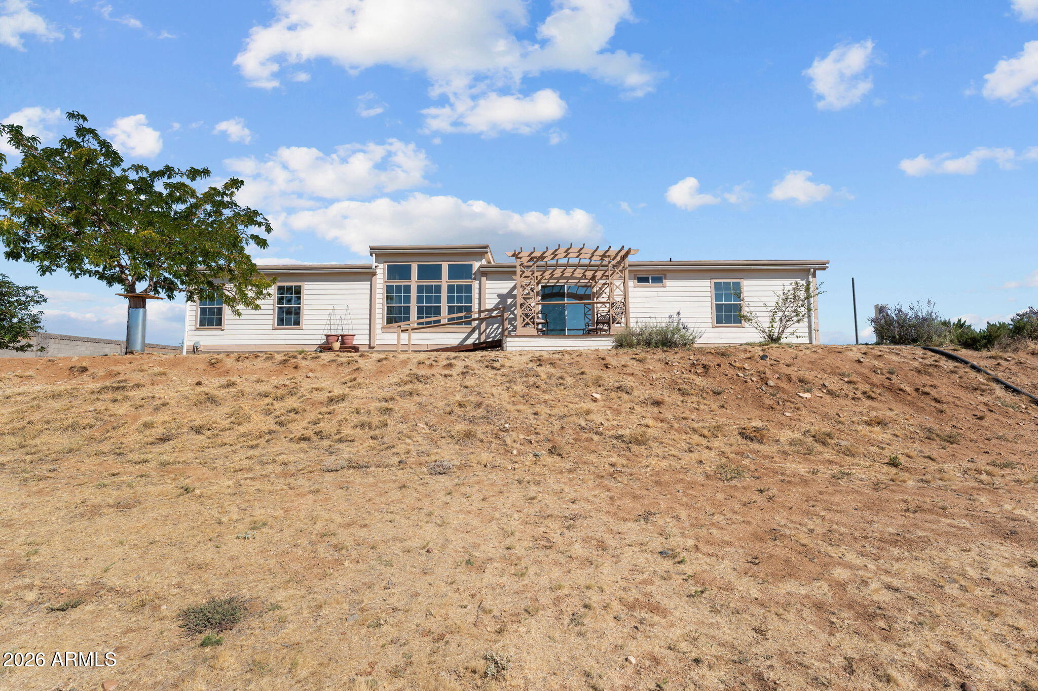 Welcome to country living with room to spread out. Located just 16 miles from the Prescott Town Square, this well-maintained home sits on 1.75 acres!  With spectacular, panoramic mountain views, perimeter block wall fencing, and plenty of space for vehicles, toys, a great horse facility or just outdoor living this is the place for you! Featuring a desirable split floor plan, this home offers comfortable separation between the primary suite and secondary bedrooms, plus a bonus/game room perfect for entertaining, hobbies, or a home office. Recent updates provide peace of mind, including a new insulated standing seam metal roof (2018), new HVAC system (2023), new hot water heater (2024), new water-resistant laminate flooring throughout (2026), and all new window screens (2026). New faucets (2026). Accessibility features include ramps and wider 36-inch doorways for added convenience. Home was constructed with 2x6 framing and has upgraded insulation in the floor and walls. Outside, enjoy desert landscaping, rain gutters, a gazebo with raised garden beds, a detached 12'x16' garage, RV access and parking, a paved driveway, and plenty of room to make the property your own. In addition there are Apple, Apricot, Plum and Peach trees! If you're looking for views, functionality, and updated systems on acreage, this property checks all the boxes.
