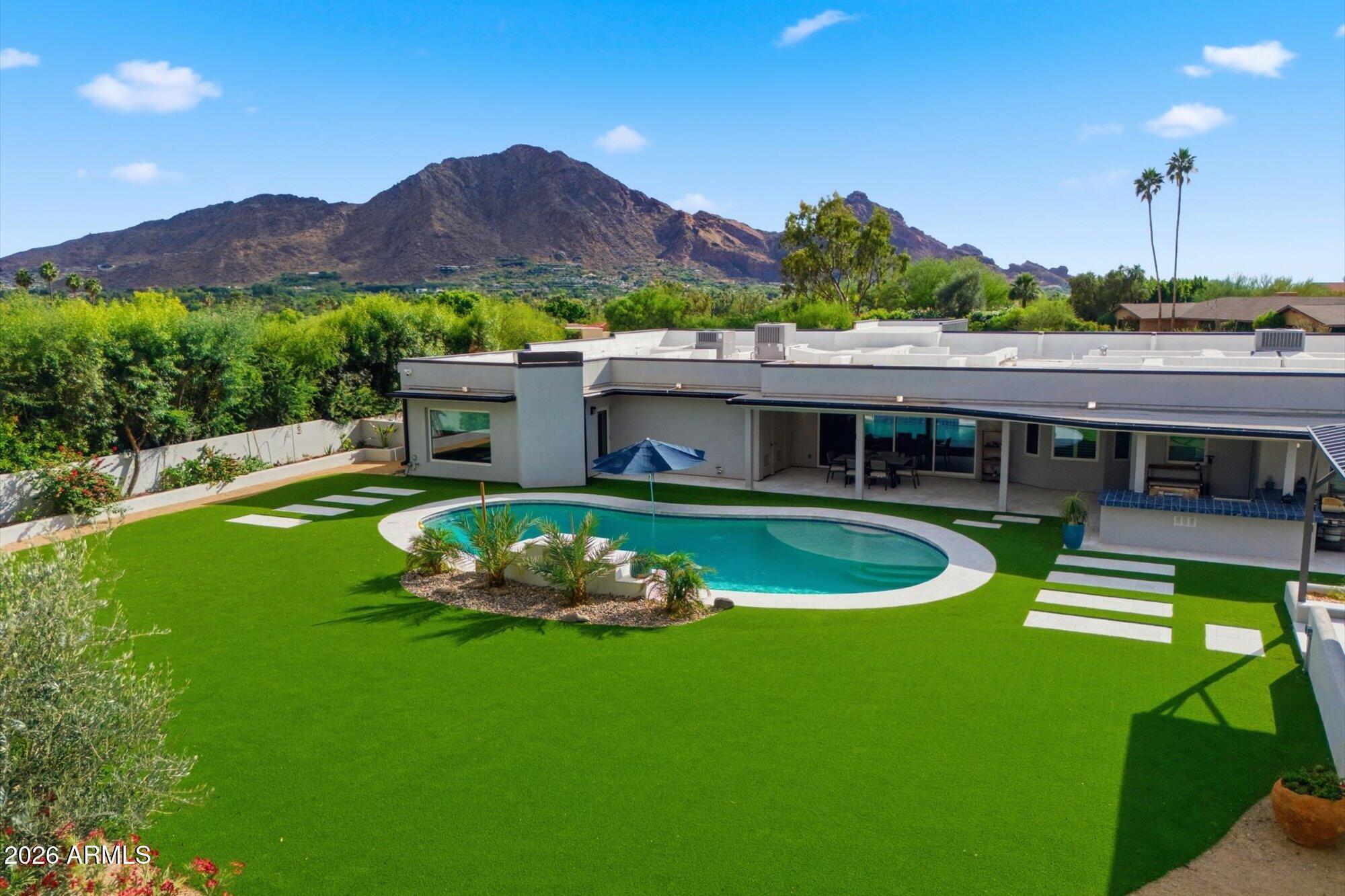 Located in the most significant neighborhood of Paradise Valley! Move right in or buy at lot value! This  totally rebuilt home with sweeping views of the north side of Camelback Mountain. This nearly 1.3-acre estate offers 5 bedrooms and 4.5 baths, plus game room! The private primary suite features a spa-like bath and is separated from a newer addition that includes a large flex room and two ensuite bedrooms--ideal for guests or multigenerational living. Entertain effortlessly in the roomy chef's kitchen and butler's pantry that open to a comfortable great room with an additional front seating area. Outdoors, enjoy an equipped kitchen, a dramatic gazebo with fireplace and pizza ovens, and ample space to add a casita, pickleball court, or extra garage. Close to everything that is PV