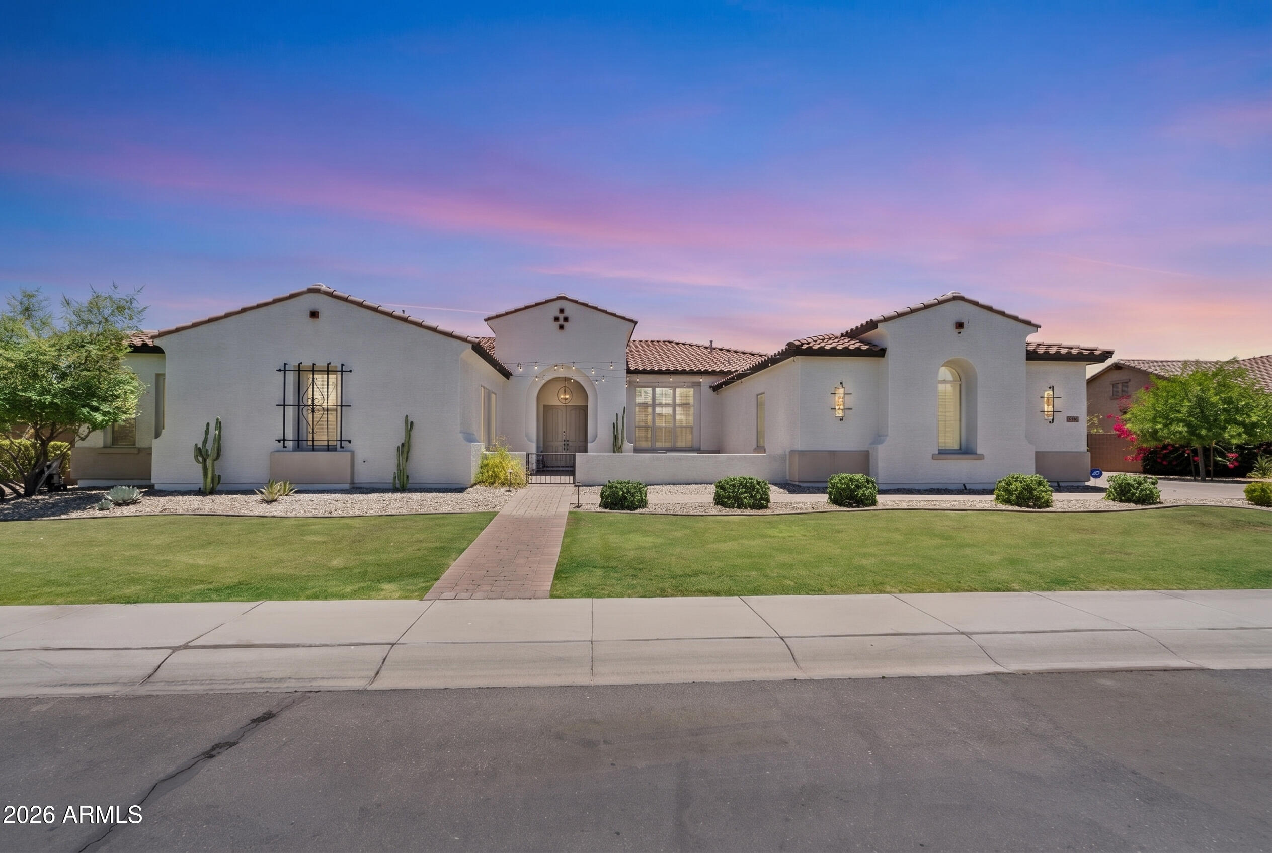 This extraordinary single-level estate has undergone a sweeping, no-detail-overlooked transformation - emerging as one of the most exceptional offerings in the East Valley. Soaring 12-foot ceilings welcome you the moment you step inside, while every space has been reimagined with designer-level finishes: white oak cabinetry, quartzite countertops, and custom lighting set the tone throughout, while curated wallpaper, frameless glass, and statement fixtures bring a sense of warmth and sophistication to every room.
The chef's kitchen is a true showpiece - anchored by a 48'' Thermador range, Thermador column refrigerator/freezer, built-in speed oven/microwave, oversized workstation sink, custom range hood, and a striking bookend quartzite backsplash. The primary suite was designed to feel like a five-star retreat, featuring a soaking tub, towel warmer, frameless glass shower with large-format tile, and elegant backlit mirrors. Even the secondary bedrooms and baths received the same meticulous attention, from white oak flooring to designer tile and high-end plumbing fixtures.
Beyond the interior, this home offers a resort-style backyard with a sparkling pool, water feature, and an outdoor Ramada built for entertaining - all within a quiet, gated community with parks and walking paths. This is more than a remodel. This is a complete reimagining of luxury living.