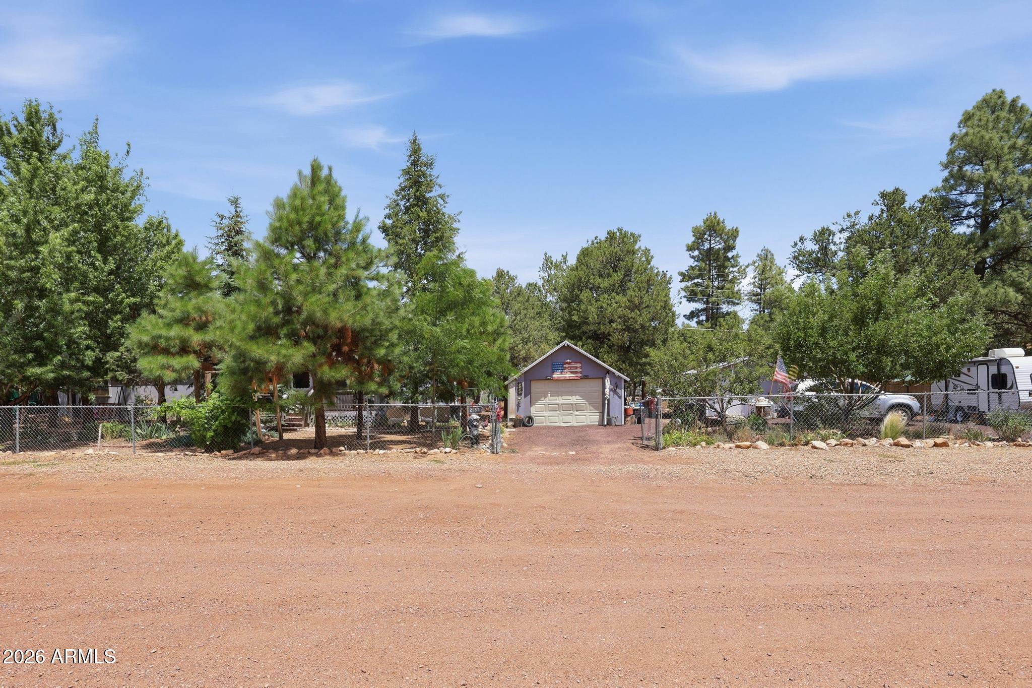 Escape to the cool pines of Overgaard in this spacious 3-bedroom, 2-bath home offering 1,568 sq. ft. on a generous 0.34-acre lot. Enjoy panoramic wooded views, a cozy wood-burning fireplace, covered deck, split-bedroom layout, kitchen island, pantry, and dual-pane windows. The property also features a detached garage, carport, workshop, storage, fenced yard, city water, paved county-maintained access, and no HOA or land lease. With a 2019 roof and updated flooring from 2015, this mountain retreat is ideal as a full-time residence, weekend getaway, or seasonal escape!