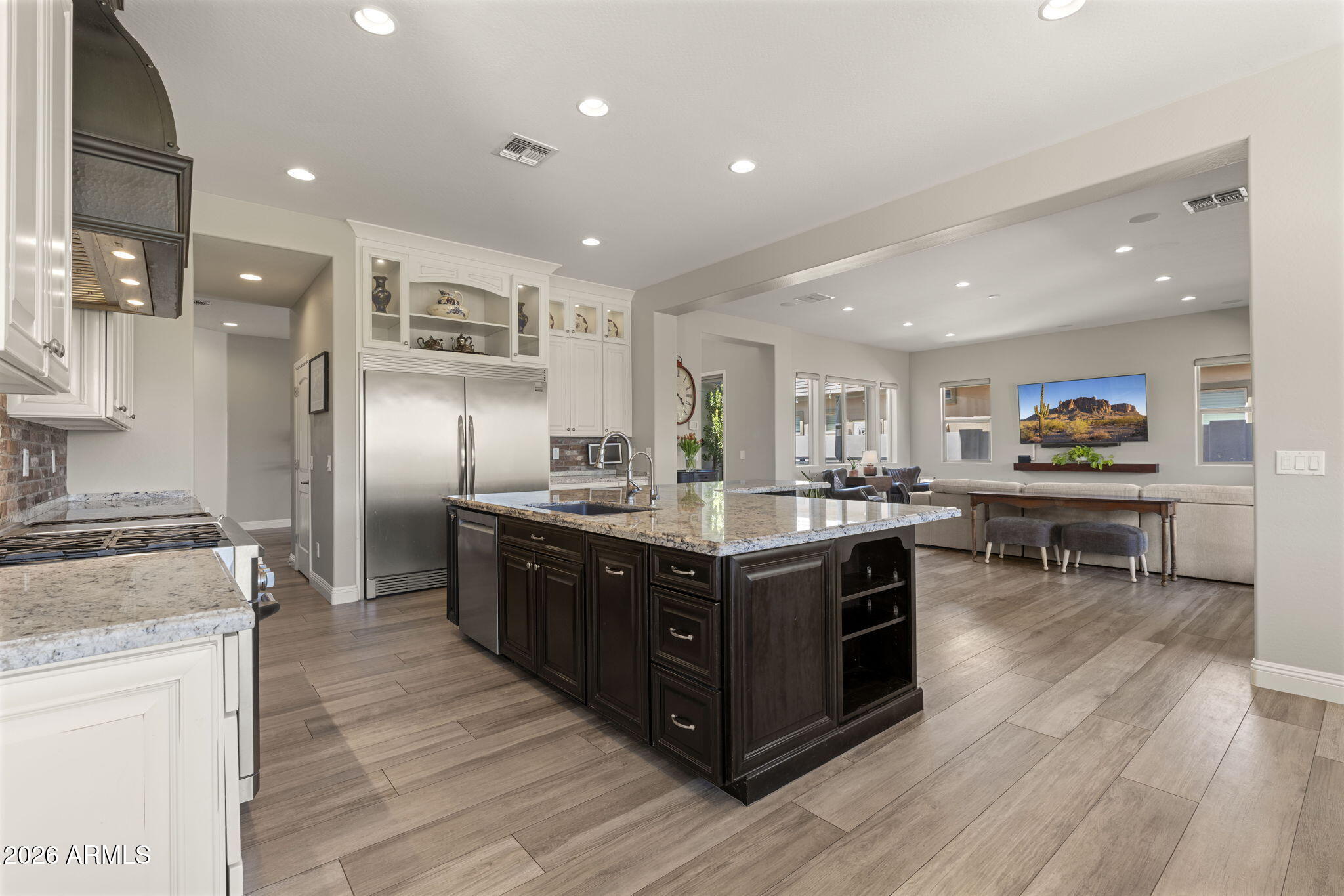 Welcome to this stunning luxury home in the highly sought-after Layton Lakes community in Gilbert, offering the perfect combination of upscale finishes, functional living space, and resort-style outdoor amenities. Designed with entertaining and everyday living in mind, the open-concept floorplan seamlessly connects the chef's kitchen, dining area, and spacious living room. The gourmet kitchen is a showstopper featuring a massive center island, granite countertops, gas cooktop, double oven, warming drawer, ice maker, custom range hood, and built-in double refrigerator. A formal dining room offers flexible use as a home office, game room, or additional living space, while the inviting center courtyard fills the home with natural light and charm. This spacious home features a desirable first-floor bedroom with privatet ensuite bath, ideal for guests, multigenerational living, or a private office setup. Upstairs, the oversized primary suite offers a luxurious retreat with a spa-inspired bathroom complete with a soaking tub, separate tiled shower, dual sink vanity, and oversized walk-in closet. Two secondary bedrooms share a convenient Jack-and-Jill bathroom, while two additional upstairs bedrooms sit adjacent to another full bathroom. A versatile loft space provides additional room for a media area, playroom, or home office. Four of the five secondary bedrooms include a walk-in closet and all have custom built in shelving. The home features tile and laminate flooring throughout with carpet only on the stairs. Step outside to your private backyard oasis featuring a sparkling swimming pool, extended covered patio, lush landscaping, colorful flowerbeds, built-in BBQ grill, and outdoor pizza oven--perfect for entertaining in Gilbert year-round. The view fence overlooks a greenbelt behind the home, creating added openness and privacy. Car collectors, fitness enthusiasts, and hobbyists will appreciate the climate-controlled 4-car garage with a tandem bay designed for extended-length vehicles and currently used as a home gym. Located in one of Gilbert's premier master-planned communities known for its lakes, walking trails, parks, splash pads, and top-rated schools (walking distance to Weinberg Gifted Academy), this beautifully upgraded home delivers the Arizona lifestyle buyers are searching for. This exceptional property is a must-see.