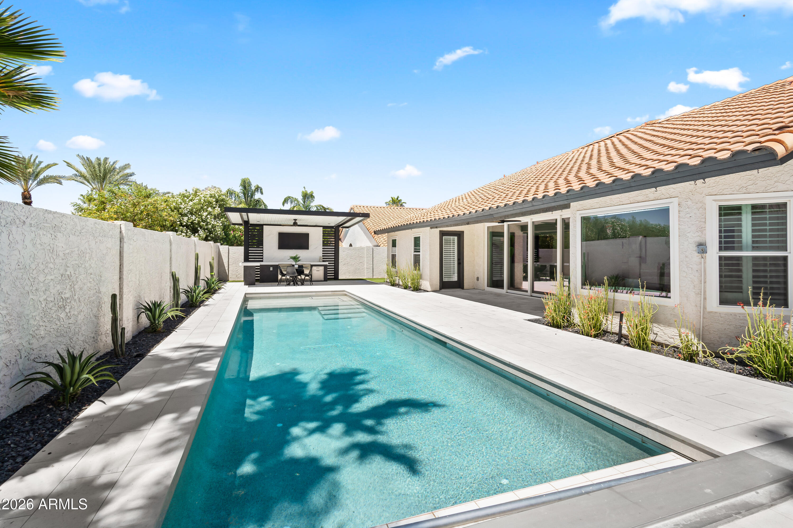 Completely reimagined and move-in ready, this stunning 5-bedroom home blends modern design with effortless indoor-outdoor living. The open-concept great room is flooded with natural light and anchored by a dramatic 16-foot slider, seamlessly connecting the interior to the newly designed resort-style backyard. The main floor features the primary suite, powder bath, laundry, formal living + dining room, with the 4 other bedrooms separately nestled upstairs. The kitchen and living spaces showcase wood-look porcelain tile flooring, shaker cabinetry, quartz countertops, and thoughtfully selected finishes for a clean, modern aesthetic. Step outside to a fully redesigned backyard built for entertaining, featuring the new sparkling pool with added Baja shelf, automatic pool cover, limestone patio pavers, low-maintenance turf, and all new landscaping and lighting. A custom ramada lounge completes the space with dual beverage fridges, a large TV area, and shaded seating for year-round enjoyment. Additional upgrades include all new windows, a mini-split system in the 3-car garage and a 220V outlet for EV charging. Situated on a quiet interior lot in the desirable Mountain View Ranch neighborhood. This home offers the perfect balance of privacy and convenience--just minutes from Scottsdale hottest dining, shopping, and everyday amenities. Opportunity is Knocking on Wood Drive. Welcome Home.
