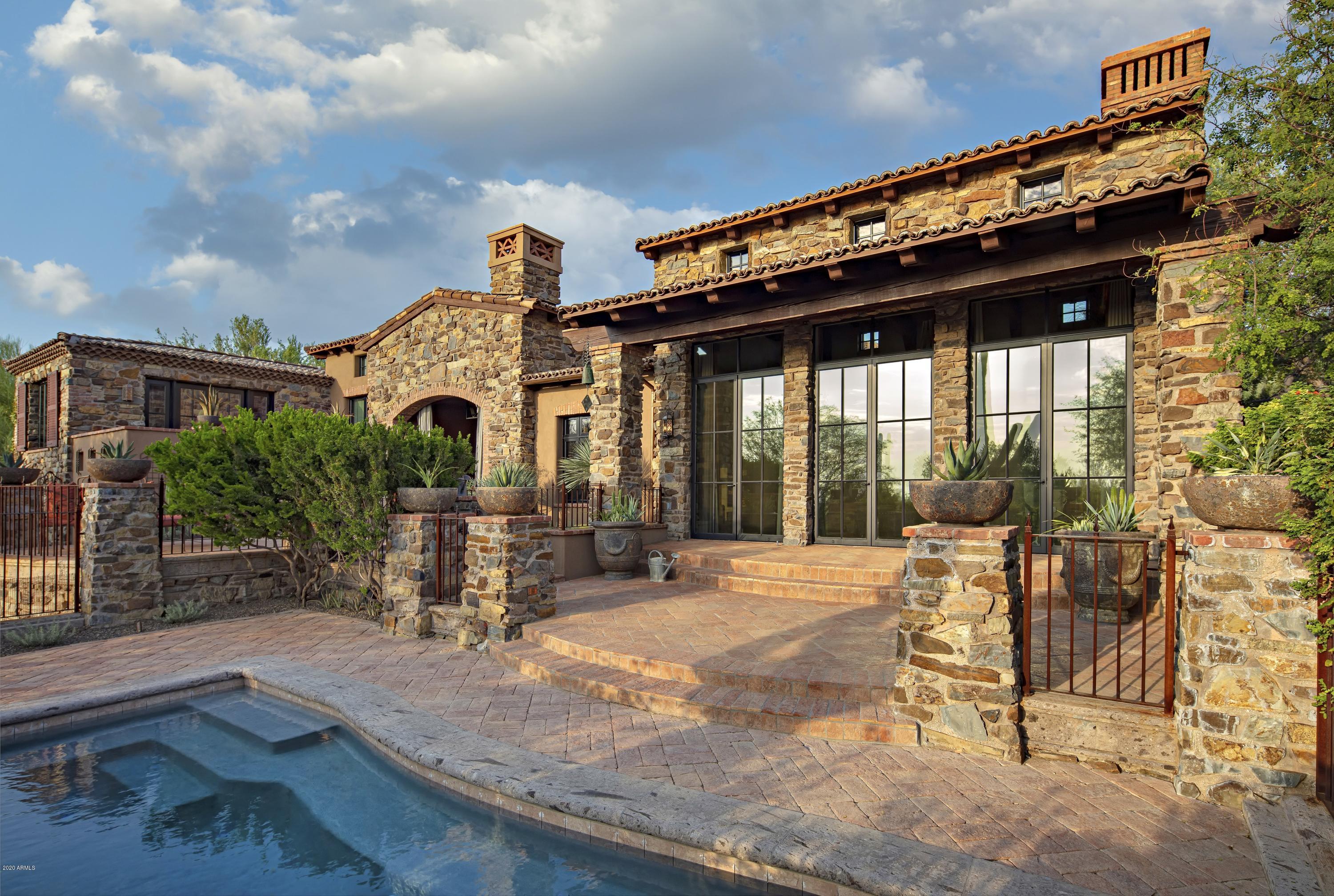 This fabulous, one of a kind, custom home has wonderful views from every window, bringing the out of doors inside. Situated on a hillside lot with the main living areas and master on the primary level for easy living.  Built around an interior courtyard which adds natural light, this home is warm and inviting with private terraces and views of Pinnacle Peak, sunsets and city lights. The residence is a product of 3 Masters of the Southwest - Mark Candelaria (architect), Nance Construction and Billie Springer (interior design). Sitting on the 8th fairway of the renowned Estancia Golf Club, it offers a sense of unmatched privacy in a mountainside setting with framed views of Pinnacle Peak across the golf course.