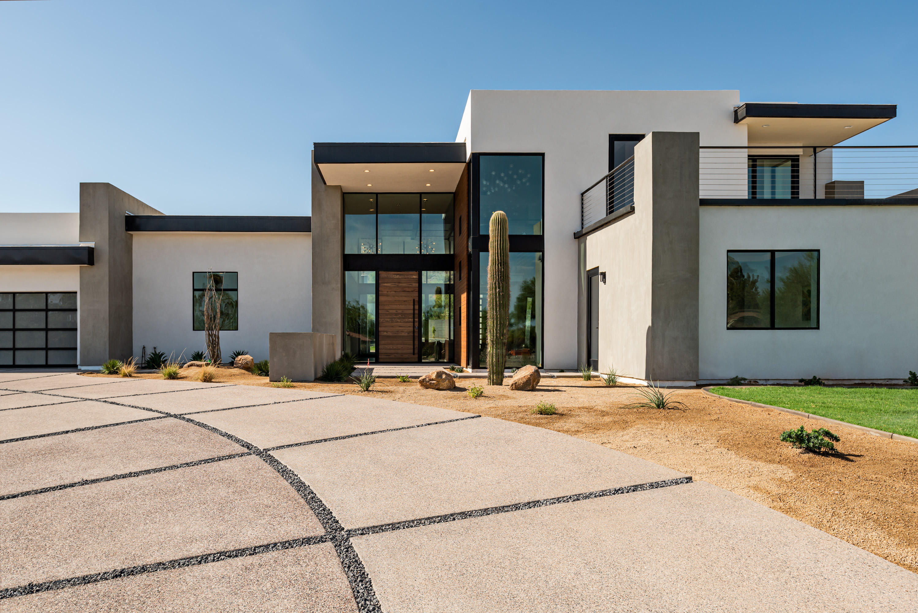 Simple sophistication and modern elegance define this stunning contemporary masterpiece in the highly desirable Paradise Valley. Newly constructed in 2019 and situated on just over an acre, find ambient, inviting spaces marked by crisp clean lines and artful design elements. Details in wood, glass and stone add style and intrigue while floor to ceiling windows frame the city lights and scenic mountain vistas beyond. Offering five bedrooms, 5.5 baths and 6,600 square feet of exquisite living space, this new home is just waiting for memories to be made. As you enter, you are greeted by Panda white marble, impressive concrete floors, lofty ceilings and welcoming, light filled spaces. Live, relax and entertain with style in the gorgeous, open concept main living. Every chef will adore the fabulous gourmet kitchen with striking custom quartz counters, convenient center island and intuitive layout pared with custom walnut and white gloss cabinets. Premium appliances including Wolf gas and induction cooktops, microwave, coffee system and double ovens, plus 60" Subzero refrigerator and two Asko dishwashers complete this space. Gather in the adjoining living room with double fireplace and sweeping views of Camelback Mountain. Pocket doors open out to the yard making for the very best of indoor-outdoor living. Linger over a delicious meal in the elegant formal dining room with temperature-controlled wine storagethe perfect bottle for pairing is always close at hand. Settle in to watch your favorite show in the media room with cultured black quartzite accent walls and full wet bar including temperature-controlled wine storage for up to 100 bottles, stunning custom walnut cabinets, beverage cooler and ice maker. Also enjoy a gym and tranquil office. 
A peaceful night's rest is found in the luxurious master suite with beautiful double-sided gas fireplace and superb ensuite boasting Statutario marble countertops, exquisite backlit floating mirrors, cultured black quartzite accents and amazing Mirabelle soaking tub. All of the additional bedrooms are spacious and comfortable with private baths. Three are located in the same wing as the master. Ideal for accommodating guests, the fifth bedroom suite sits on the upper level just off of a beautiful lofted lounge area with access out to a spacious view deck. Out back, your private oasis awaits. Grill out in the summer kitchen, take a dip in the pool with spa, lounge in the sun, or sit around the firepit and swap stories under the stars.  Also find a large garage which can accommodate five cars offering four bays plus a lift. Dramatic beauty, sheer elegance and a luxurious lifestyle await. 


Dramatic beauty, on a grand scale, sheer elegance and extreme luxury