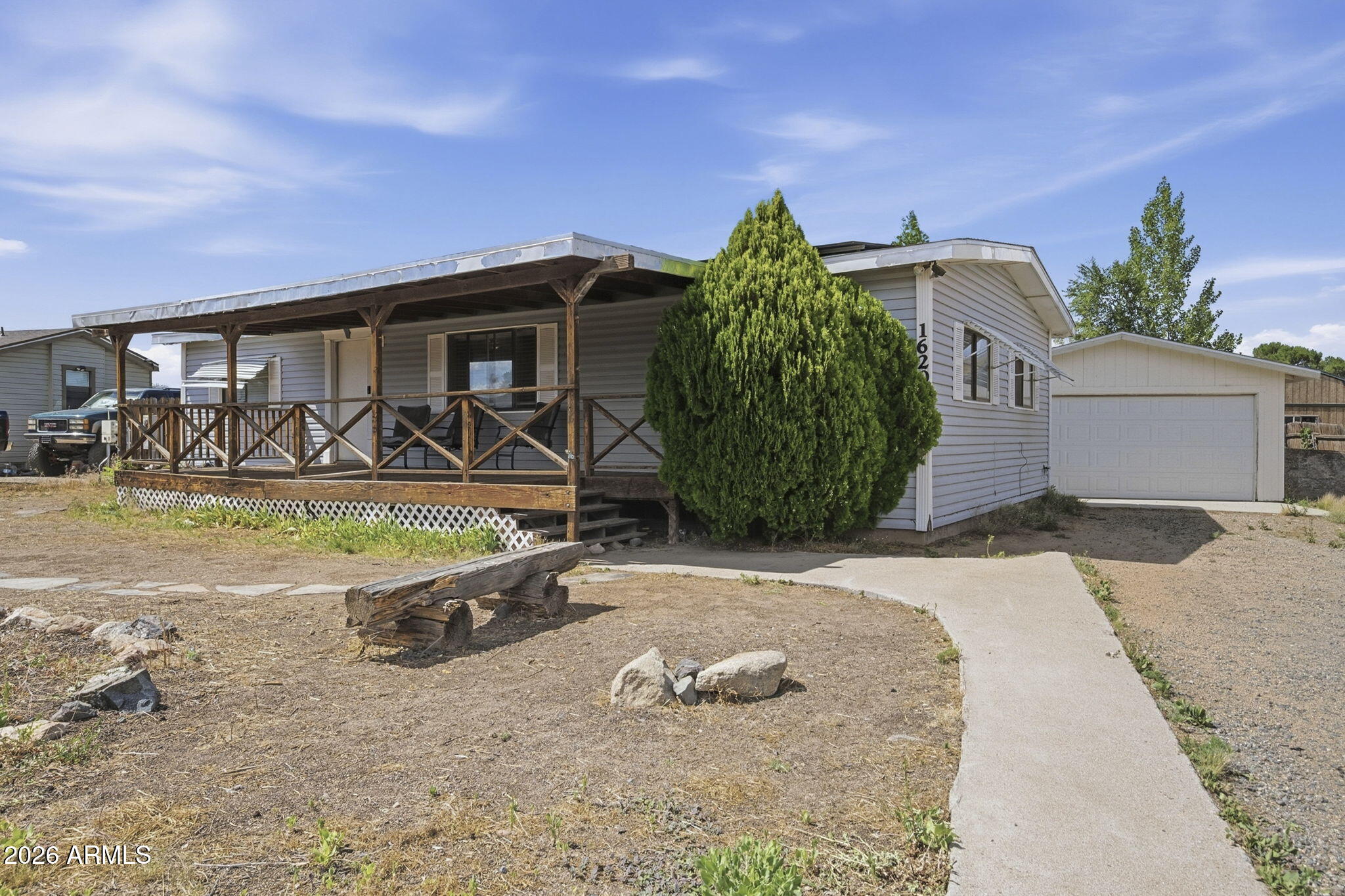 This 3 bdrm/2bath double-wide features a spacious, desirable split floor plan with vaulted ceilings. The open-concept living and dining areas create an inviting atmosphere perfect for everyday living and entertaining. Enjoy relaxing on the covered front deck, perfect for morning coffee or evening sunsets. The detached 2-car garage and off-street RV parking offer ample parking, storage, or workshop space. Enjoy the benefits of a leased solar system for potential utility savings. This property combines comfortable living, practical amenities, and energy-conscious features in a welcoming setting. Gas stubs available for range & dryer. No neighbors directly across the street provides added privacy. Remarks continued... With great bones and plenty of potential, this home is ready for your personal touch and upgrades. Welcome home!