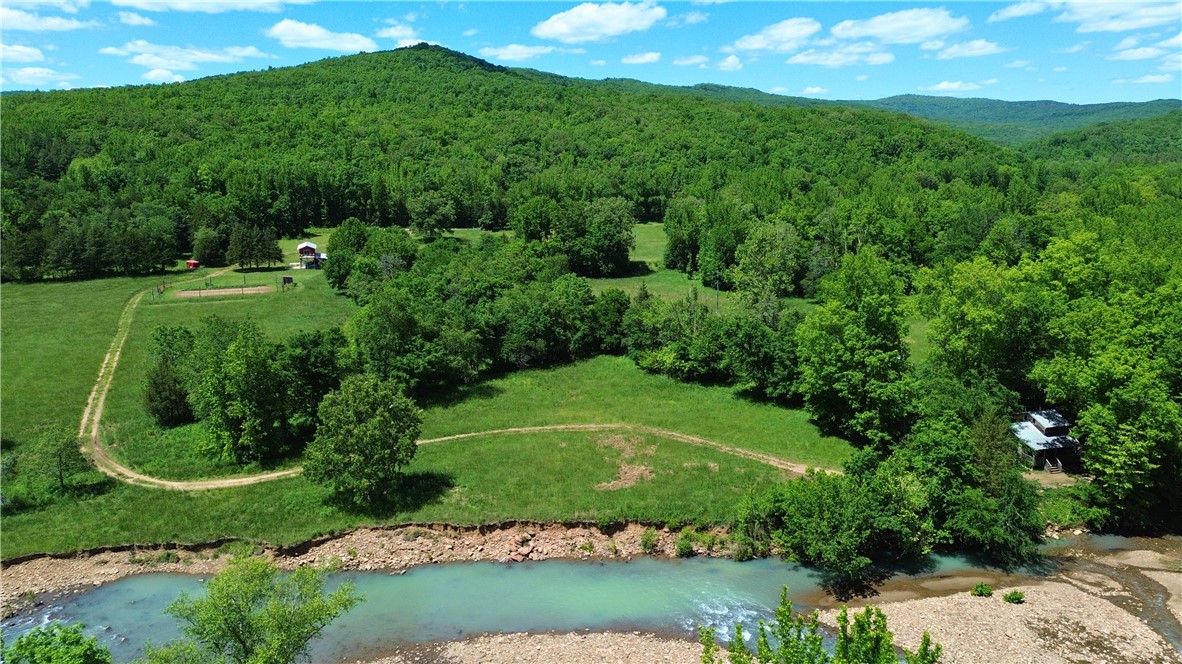 11 +/- scenic acres on Little Mulberry Creek near Friley, AR with approximately 615 feet of creek frontage and Ozark National Forest access directly across the creek. This peaceful property features a cozy 2 bed, 1.5 bath cabin with approximately 700 sq ft and an incredible creekside setting where you can relax to the sound of flowing water year-round. 

The property also includes a barn with partially finished living quarters, an established fenced garden area, and approximately 6 acres of pasture offering room for livestock, recreation, or gardening. Both the cabin and barn are serviced by a water well, and fiber optic internet is available at the road. A great opportunity for a weekend retreat, hunting property, homestead, or full-time residence in the Ozarks.