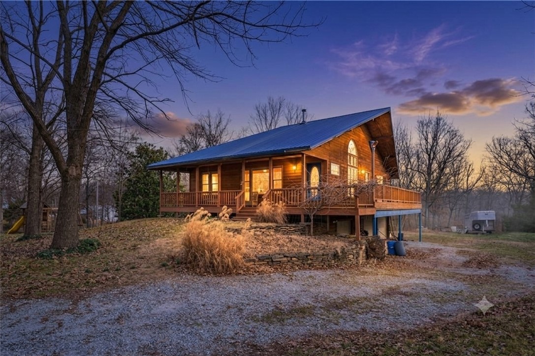 Country living without sacrificing accessibility! This property is just 15 minutes from Walmart HQ and Downtown Bentonville, making it a rare opportunity to live sustainably while staying connected. With the perfect blend of privacy, quality craftsmanship & convenience, this exceptional property is mostly flat and highly usable—ideal for homesteading. The cedar cabin offers timeless character and solid construction, 2 bedrooms & 2.5 baths with three-quarter-inch hardwood flooring throughout. Solid oak cabinets anchor the kitchen, double-paned windows and a whole-home water softener add comfort and efficiency. The home is well insulated with Thinsulate 6" on exterior walls and 4" on interior paired with a metal roof. A large 3-car garage with insulated doors is supported by steel beams, as is the porch, for long-term durability. Additional features include frost-proof drains, a laundry chute, & seasonal wisteria trees that grace the porch with color and charm.  Parcel IDs to be assigned after accepted contract.