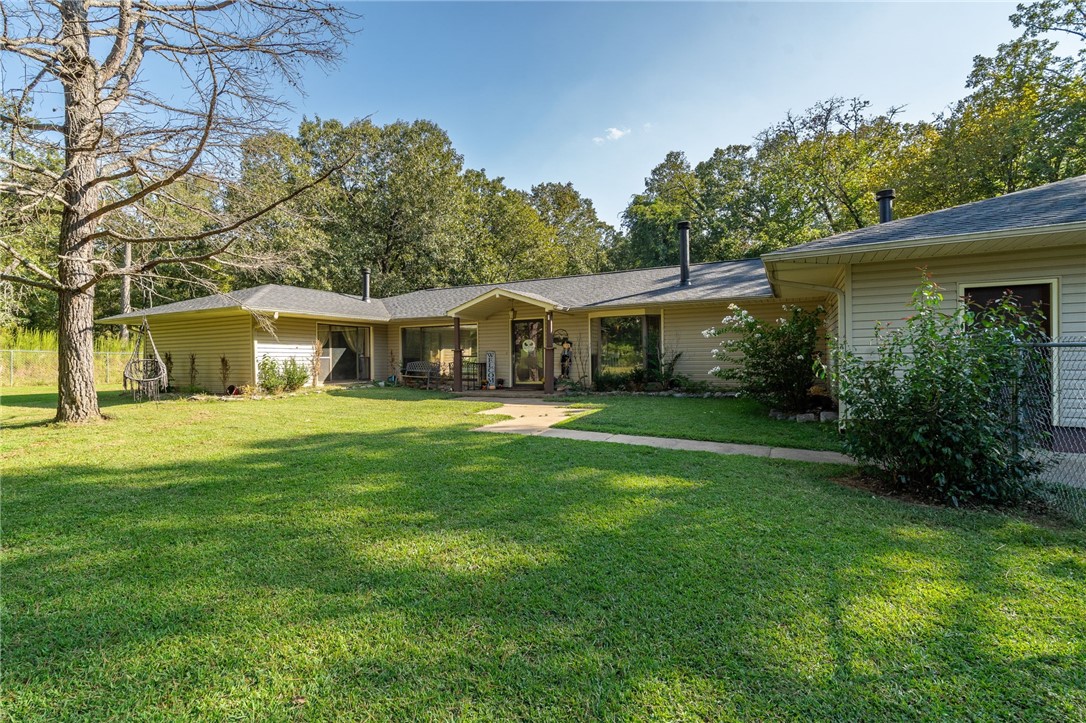 Find seclusion, nature, and comfort all within Greenwood's award-winning school district! This beautiful home boasts a spacious split floorplan, tall cathedral ceilings, tons of natural light, and the kind of charm you'll only find in Arkansas. Soak in all the scenery that the Natural State has to offer with a screened-in sunroom, a large back patio, a quiet pergola overlooking a large stocked pond, a seasonal creek, and 20.12 acres ± with wildlife galore! Although very quiet and secluded, this home is just 15 minutes away from downtown Greenwood and 30 minutes from Fort Smith. The home has many updates, including a new roof, 3 new mini split heat & air units that allow each bedroom’s temperature to be controlled independently, a new septic system, and many fresh touches throughout the house! There are two working wells on the property, although the house is connected to city water. This home offers 3 wood fireplaces AND a wood furnace, keeping your heating costs extremely low!