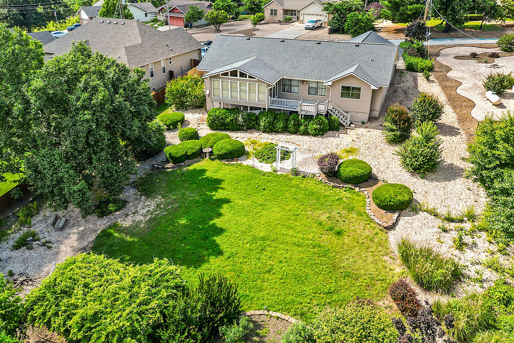 This exceptional Bella Vista location offers scenic seclusion combined with quick access to the famous Oz Trails network, local lakes, and regional highways. Step through the inviting entryway into a light-filled living room, anchored by vaulted ceilings and a cozy gas fireplace. Designed for effortless prep, the kitchen maximizes utility with a dedicated pantry, breakfast bar seating, and large countertop space for cooking. The thoughtful split-floor plan places 2 generous guest bedrooms with walk-in closets—conveniently near a shared full bath and dedicated linen storage. The spacious primary suite serves as a true sanctuary, a walk-in closet with custom built-in shelving and direct access to a spectacular enclosed sunroom equipped with a mini-split for year-round comfort.  The sunroom and adjoining, durable Trex deck offer the perfect vantage points to take in the peaceful, expansive backyard views. Whether you are a daily commuter or an outdoor enthusiast, this home is ready for your own personal touch.