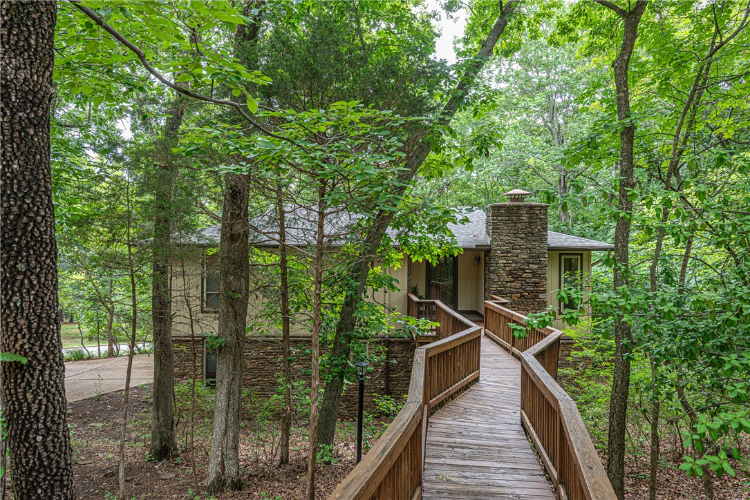 WELCOME HOME! Nestled in the heart of Fayetteville this beautifully updated 4 bedrm, 2.5 bathrm home on a corner lot offers privacy, character, & comfort! Min from I-49, U of A, Downtown, & Mt Sequoyah. Enjoy a treehouse-like entrance w/ bridge to front porch. Head inside to stylish entry foyer w/ built-in bench! Cozy living rm w/ laminate wood flooring  opens to dining area & Ushaped kitchen feat: built-in hutch & desk, two-toned cabinetry, granite counters, separate oven & glass cooktop! Off the kitchen enjoy your covered upper deck! Main floor feat: 1st primary bedrm w/ pass-through bathrm to 2nd bedrm! Split floor plan w/ downstairs being the ultimate space feat: LVP Flooring, wet bar, large dining space or game table area, spacious 2nd living w/ rock fireplace, powder bathrm, & guest bedrm. Relax  in the lower-level primary suite w/ plenty of closet space & private ensuite w/ double sink vanity & modern walk-in shower! Off the lower level enjoy another large deck surrounded by your mature tree canopy! Act now!